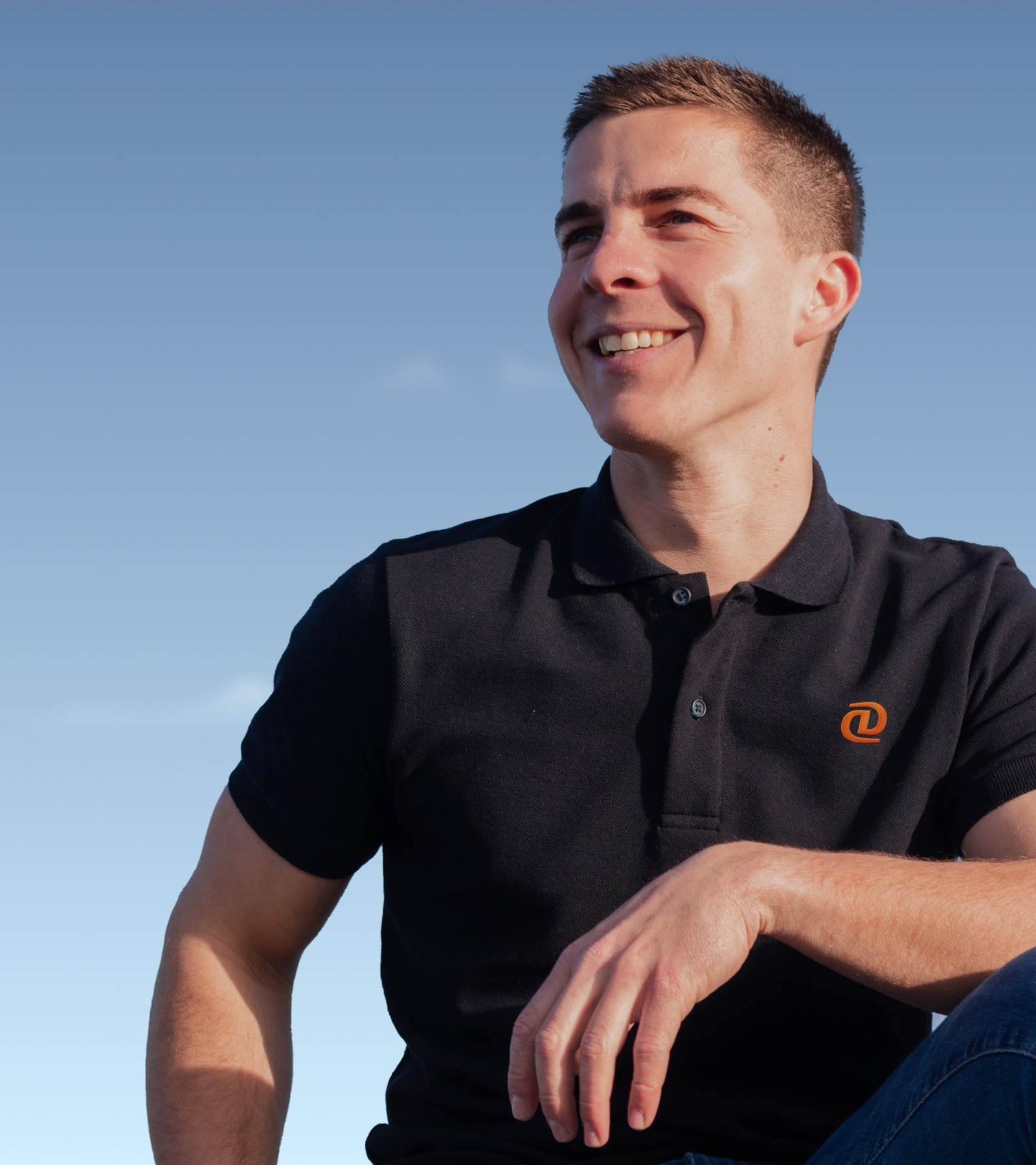 Black polo shirt embroidered with the orange DataDocks symbol