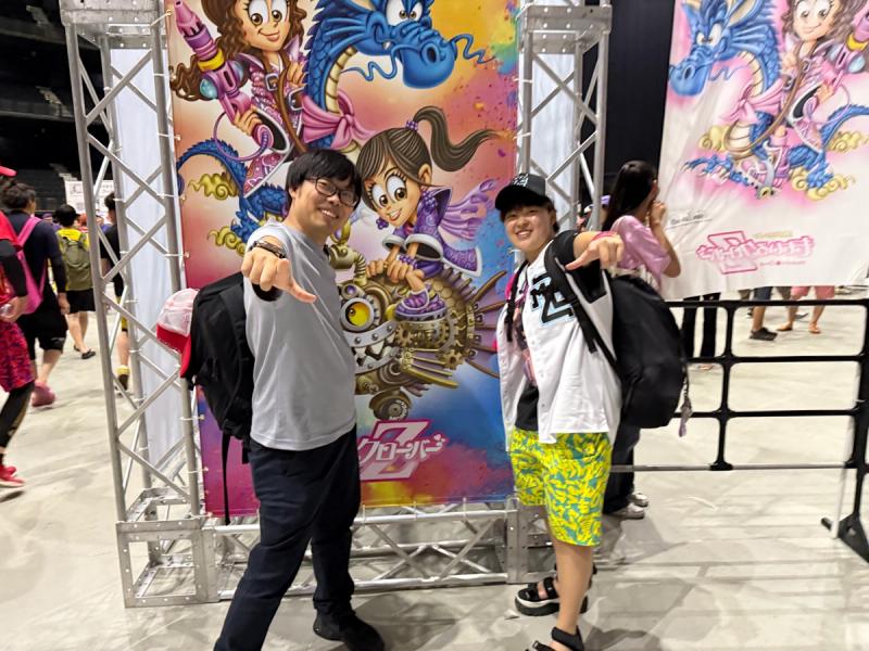 ポスターを背に中村社長と早川さんがポーズを取っている写真