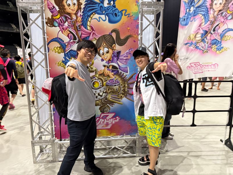 ポスターを背に中村社長と早川さんがポーズを取っている写真