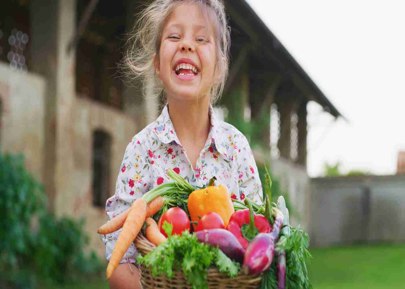 Cute little girl holds basket of vegetables