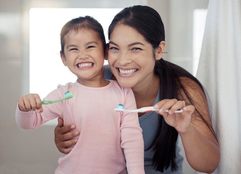 Cute little girl and mom smiling have fun brushing their teeth