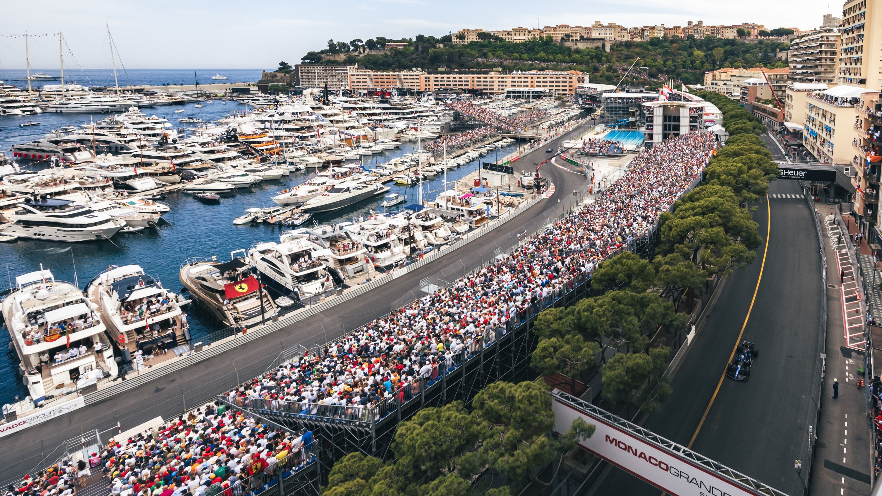Monaco Grand Prix track with yachts and crowd.
