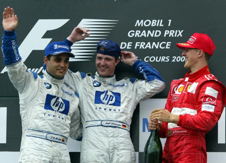 Ralf Schumacher celebrates on the podium with Williams teammate, Juan Pablo Montoya, and brother, Michael Schumacher, after winning the 2003 French Grand Prix 