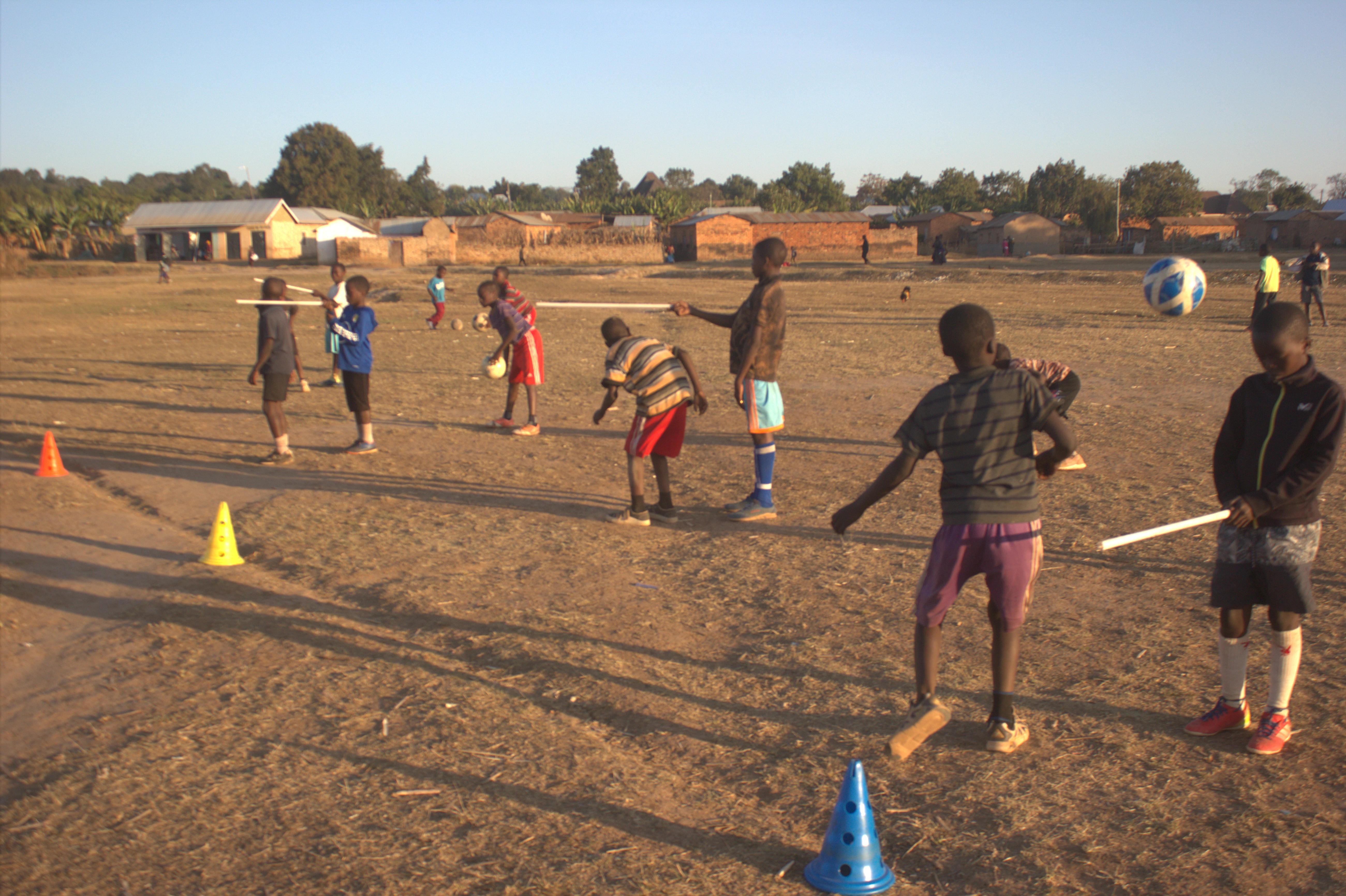 Players working through cone drills on a dusty field at sunset