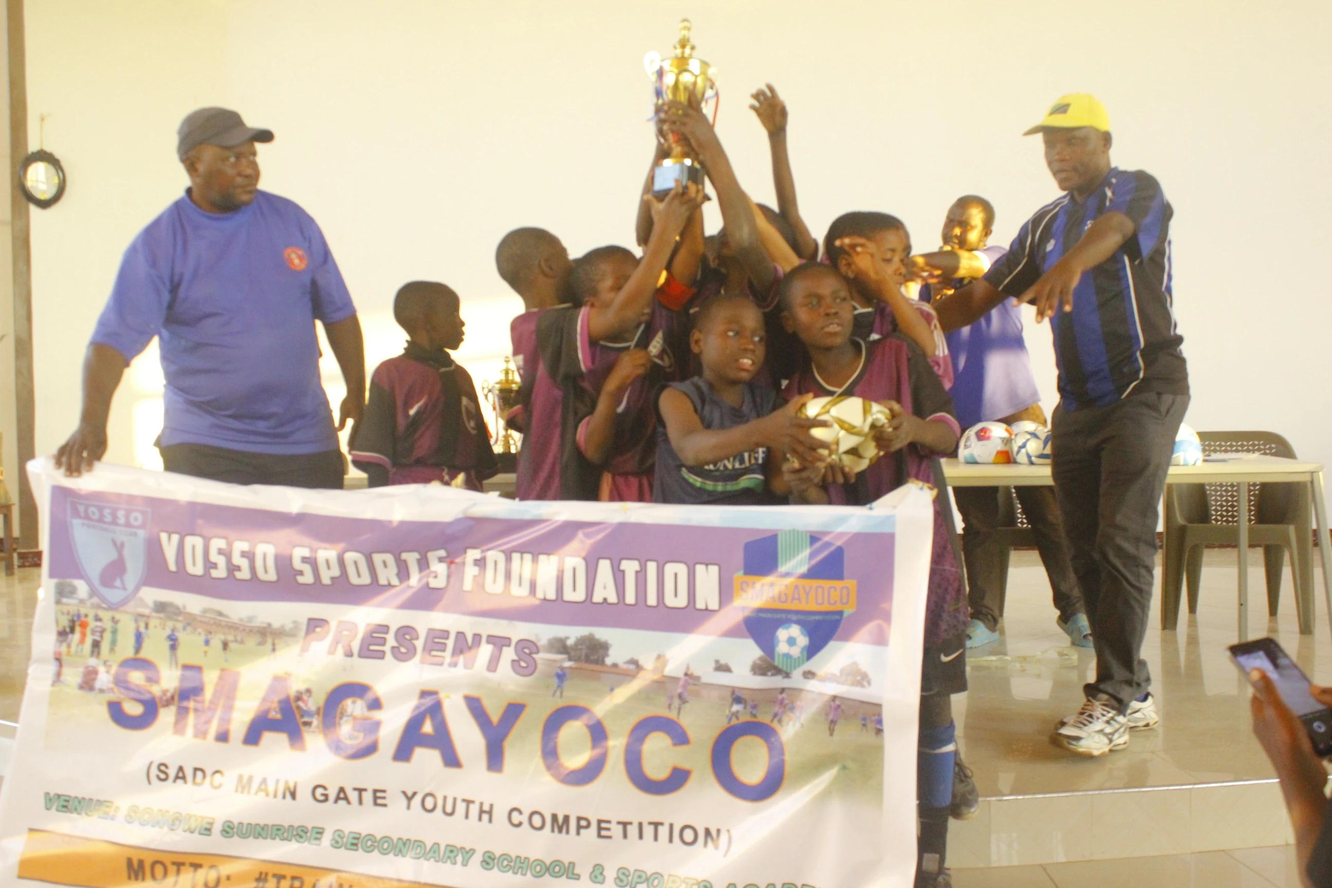 YFC U11 players celebrating together while lifting the SMAGAYOCO Tournament trophy.