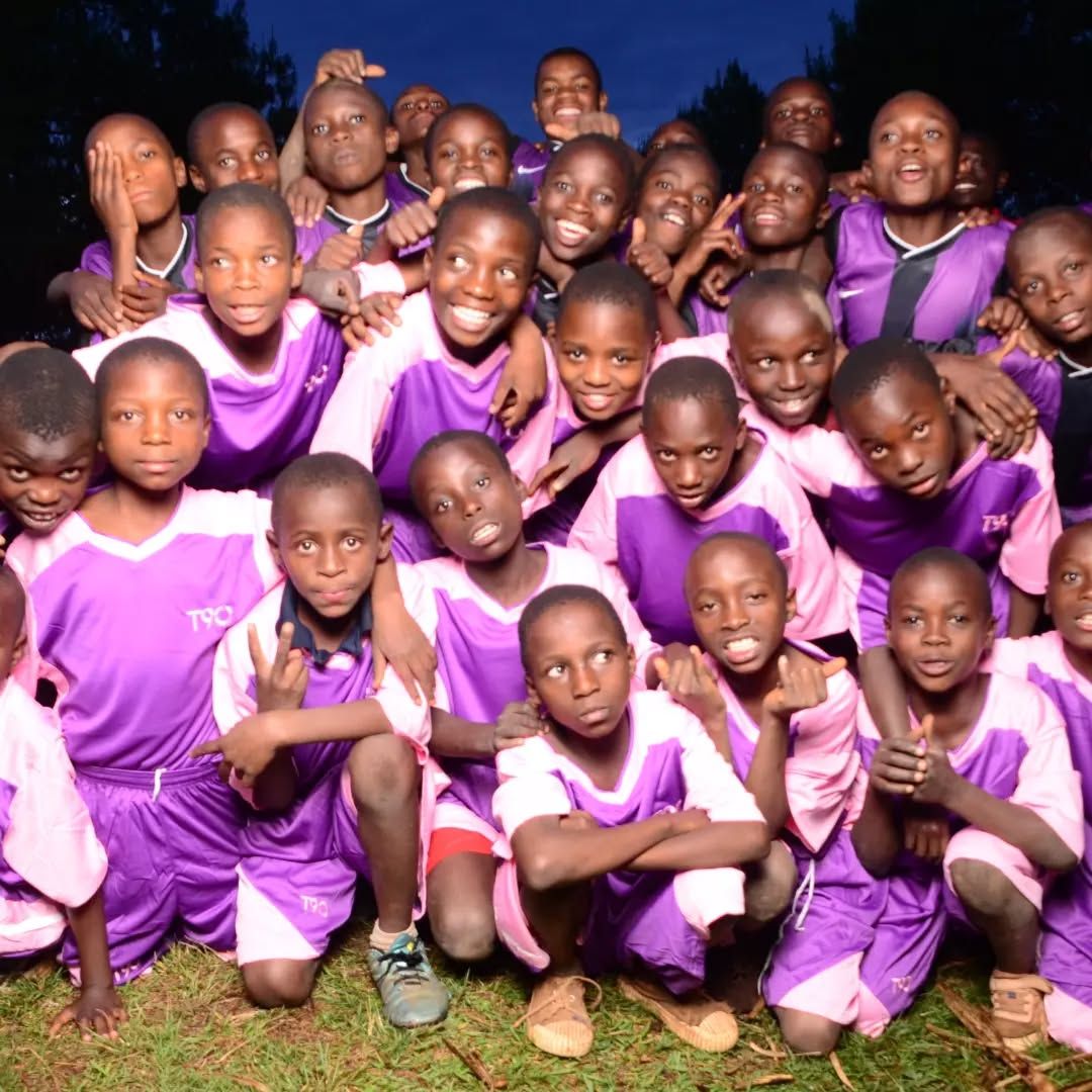 Large group of players in purple and pink kits posing together at dusk