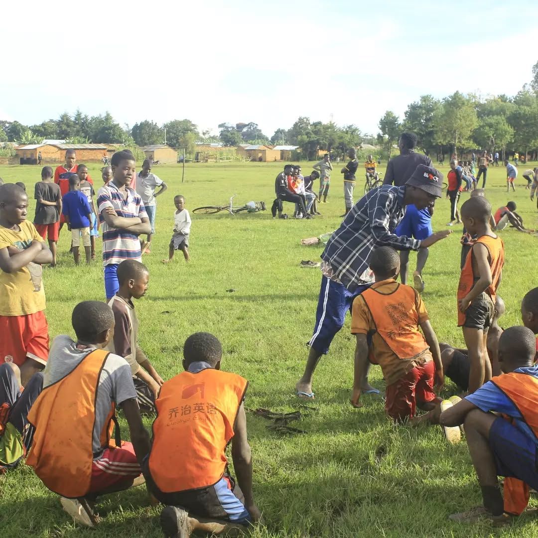 Coach instructing players in orange bibs on an open field