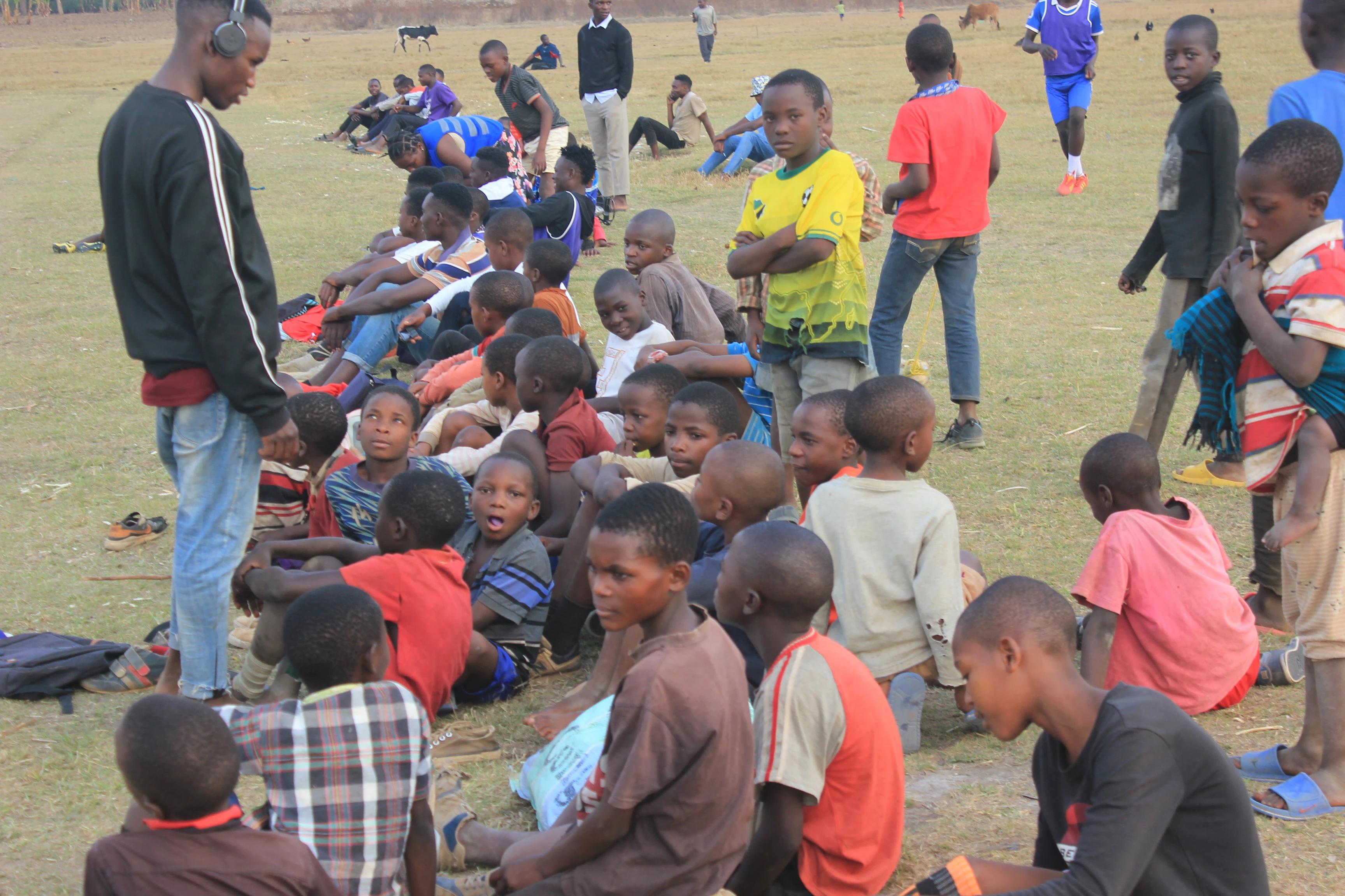 Youth resting on the field as a match continues in the background