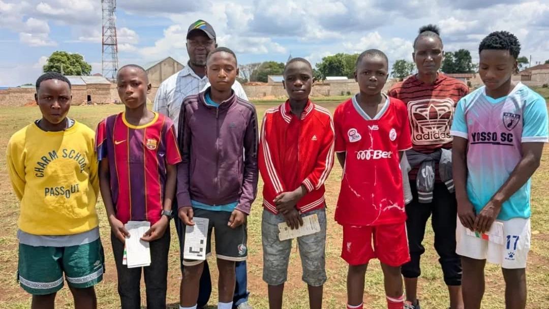 Young football players and coaches standing together on a football field following a player screening activity in Mbozi.
