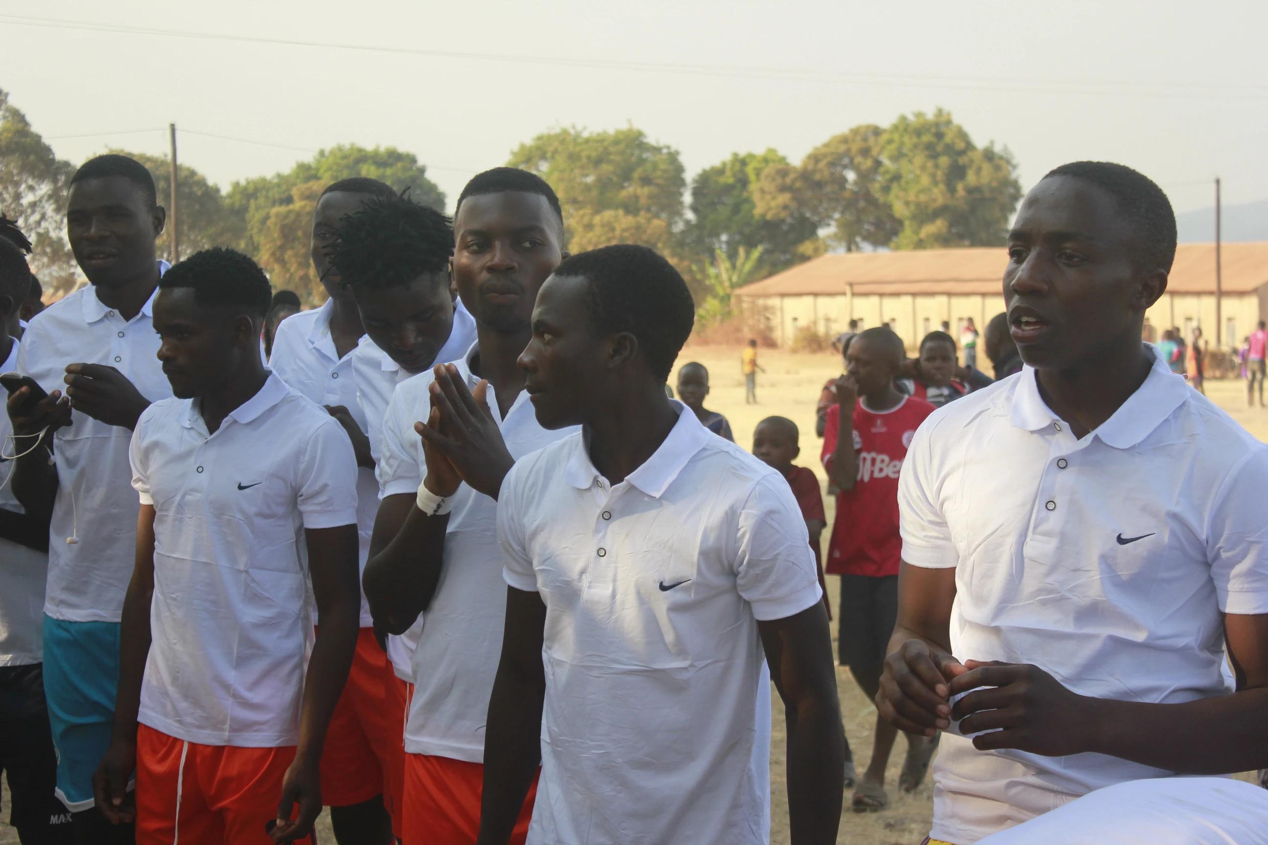 Group of young men in matching white polo shirts standing outdoors