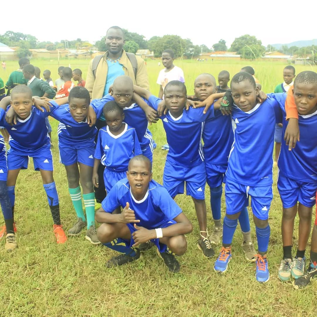 Youth team in blue jerseys posing together with their coach