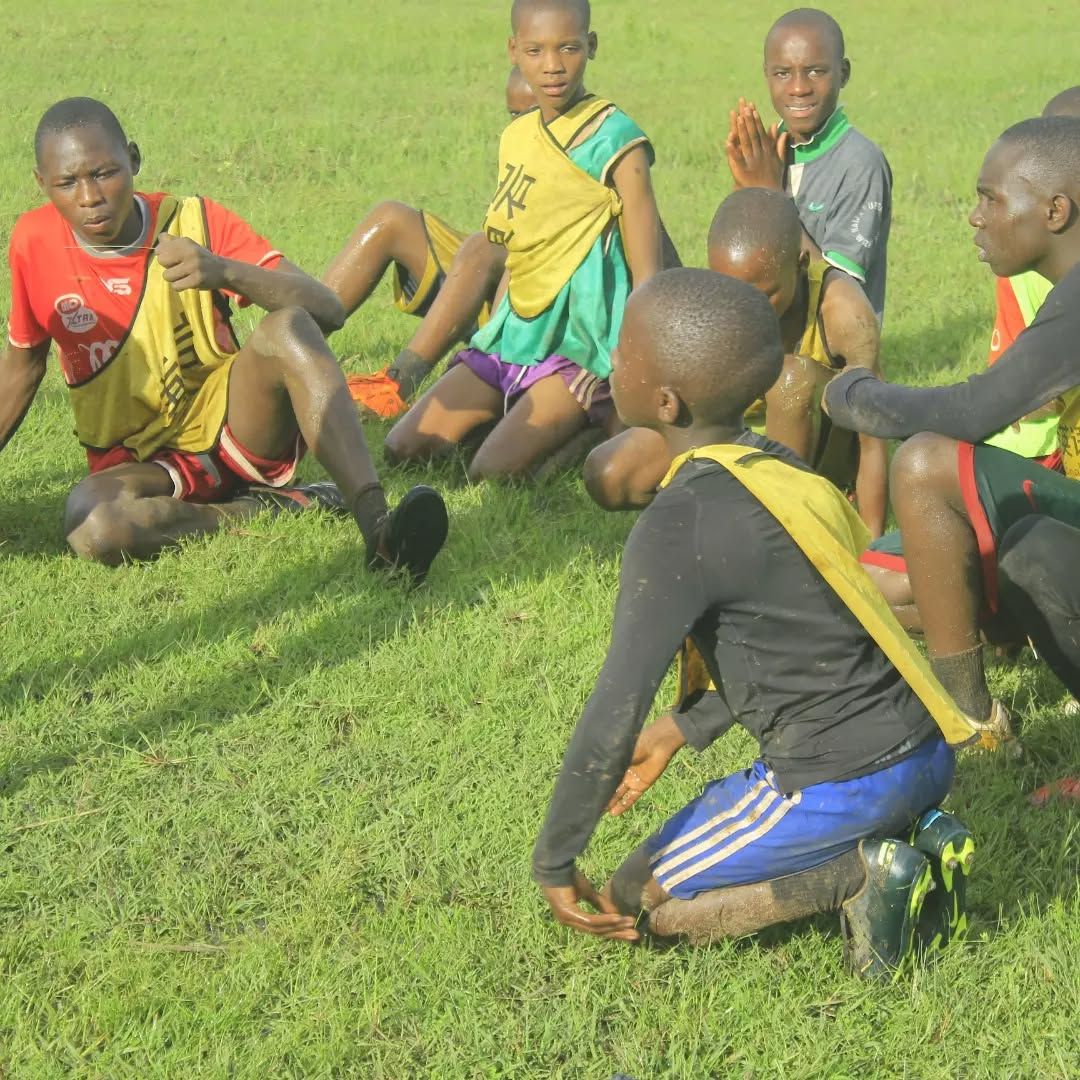 Players in muddy training bibs seated together on grass