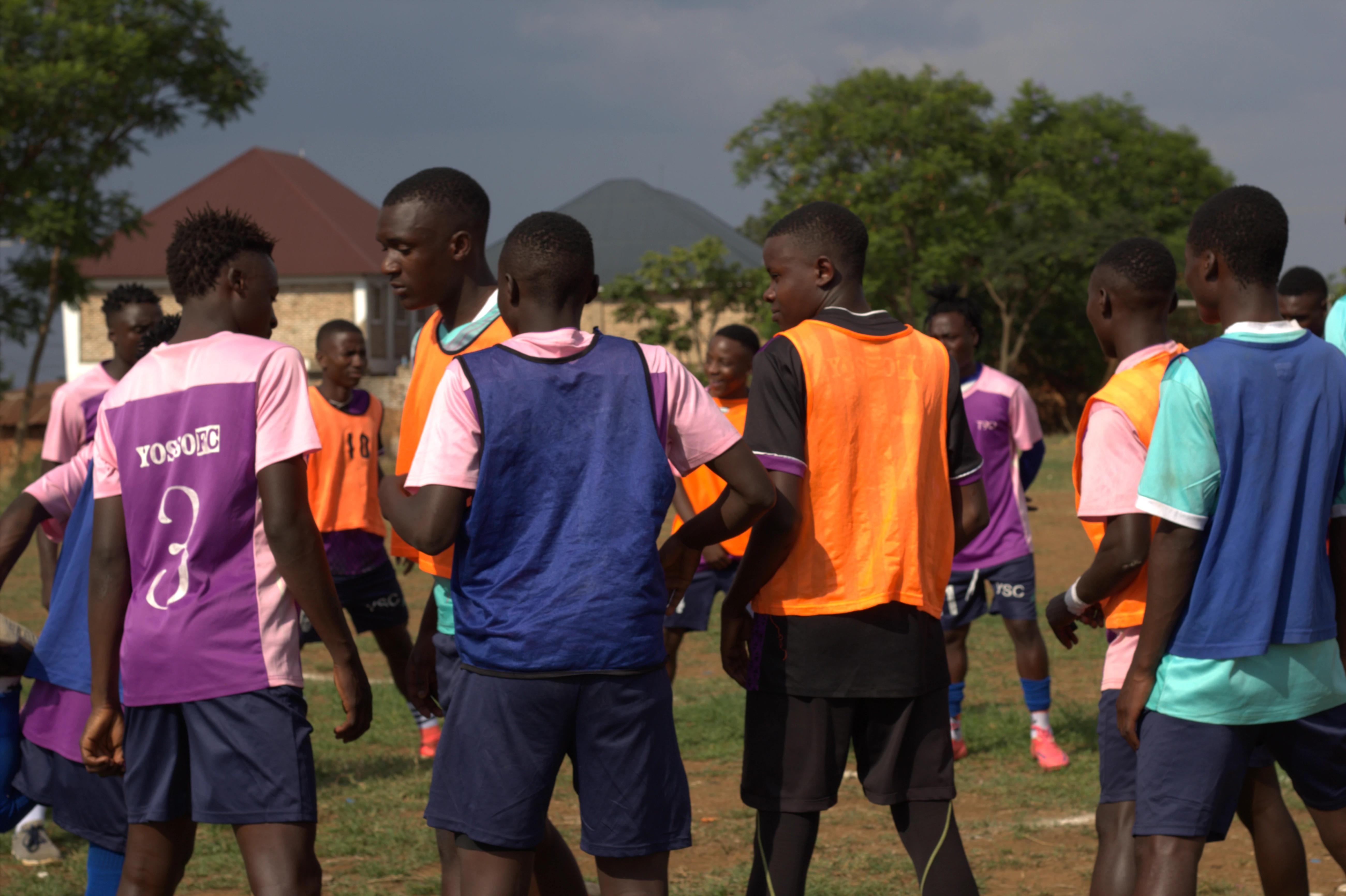 Yosso FC players in training bibs gathered under a stormy sky