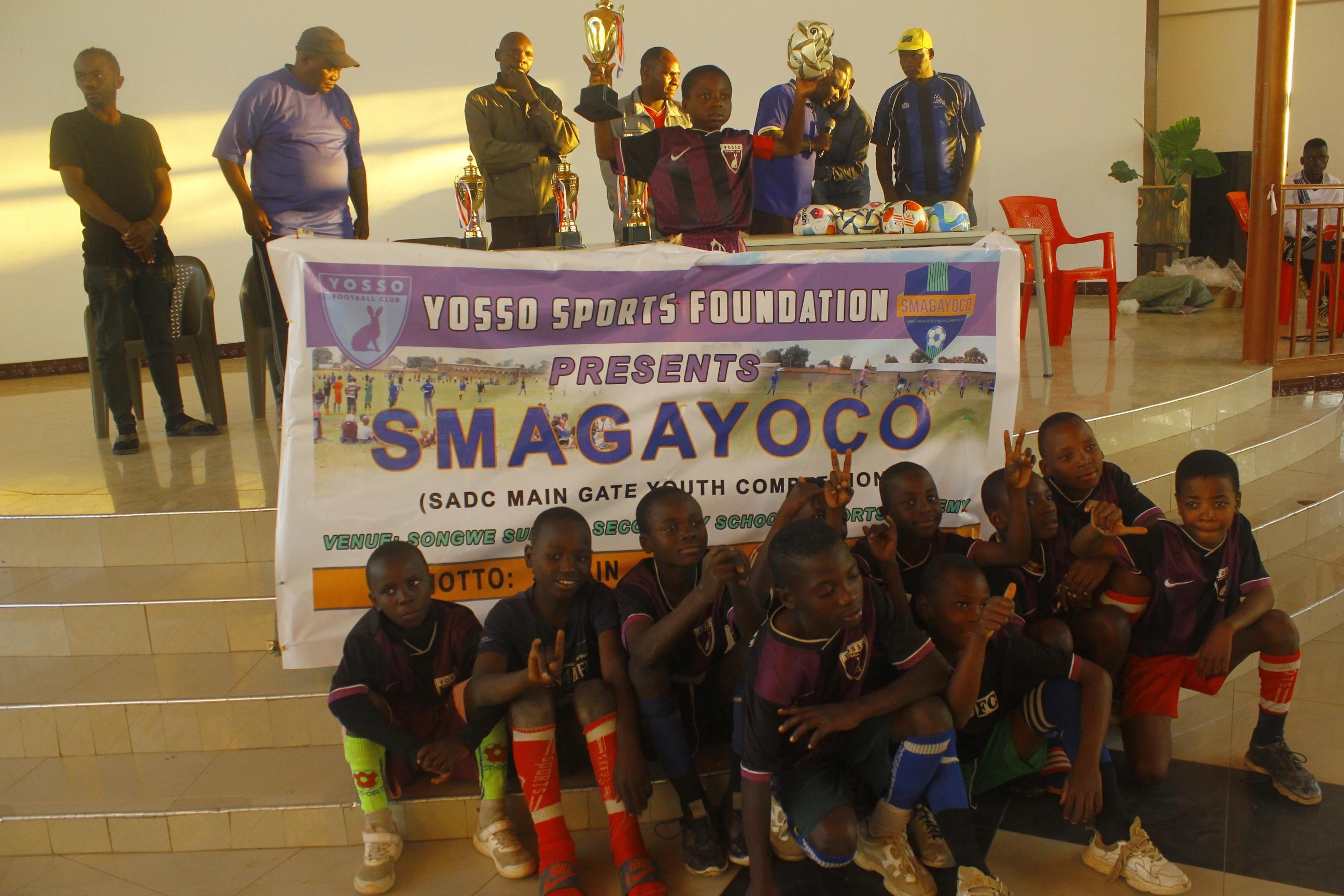 Youth football team posing with trophies in front of the SMAGAYOCO banner