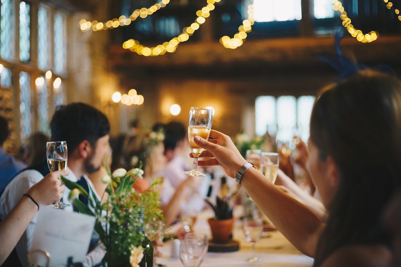 Wedding goers raise glasses of champagne in barn setting.