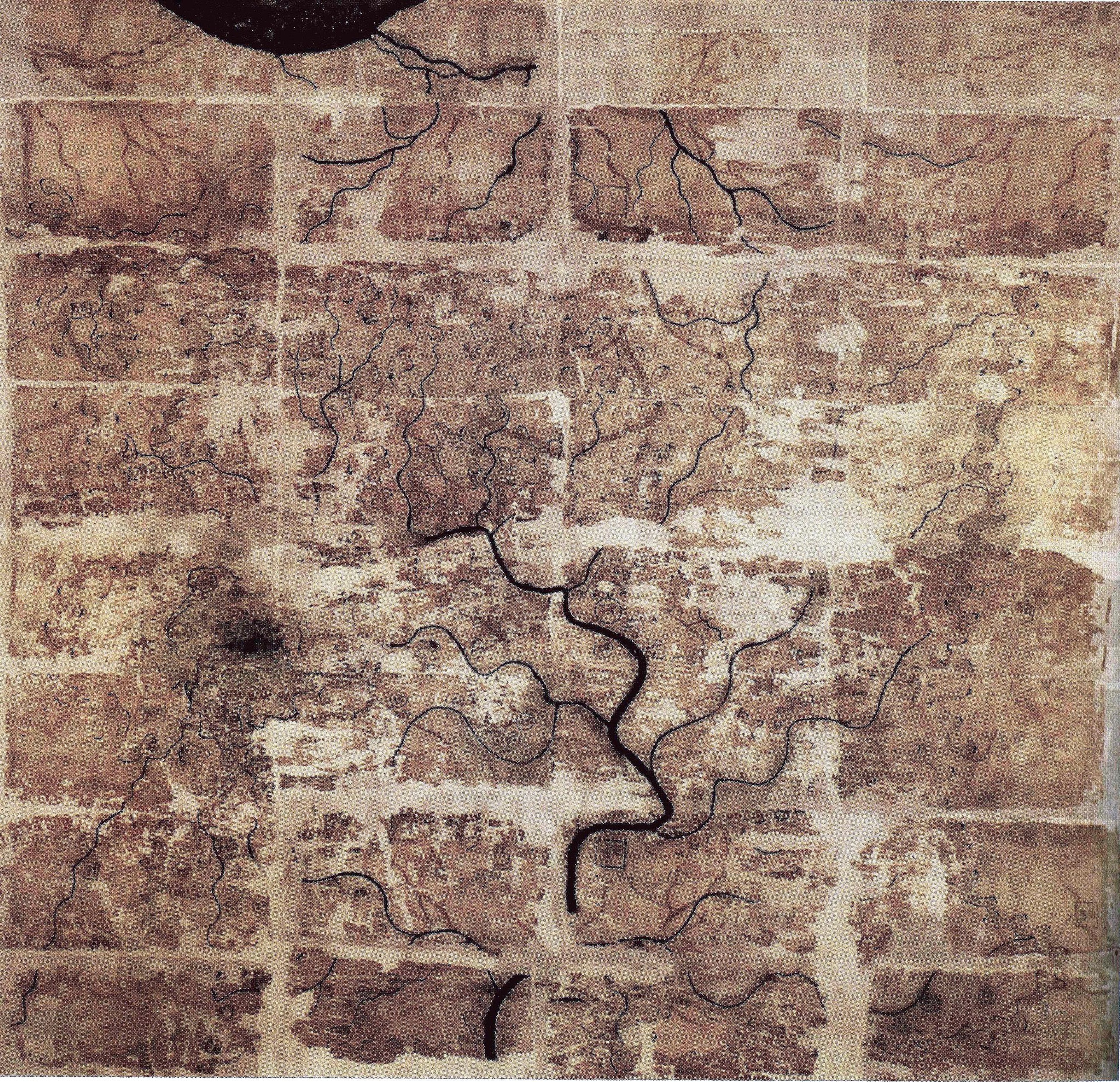 Image showing an ancient map which is produced on silk. The map is oriented south and shows depicting the Kingdom of Changsha and Kingdom of Nanyue in southern China. It is brown and beige in colour, with faded markings showing rivers and mountains. The map shows historic folds, with areas of wear and fabric loss