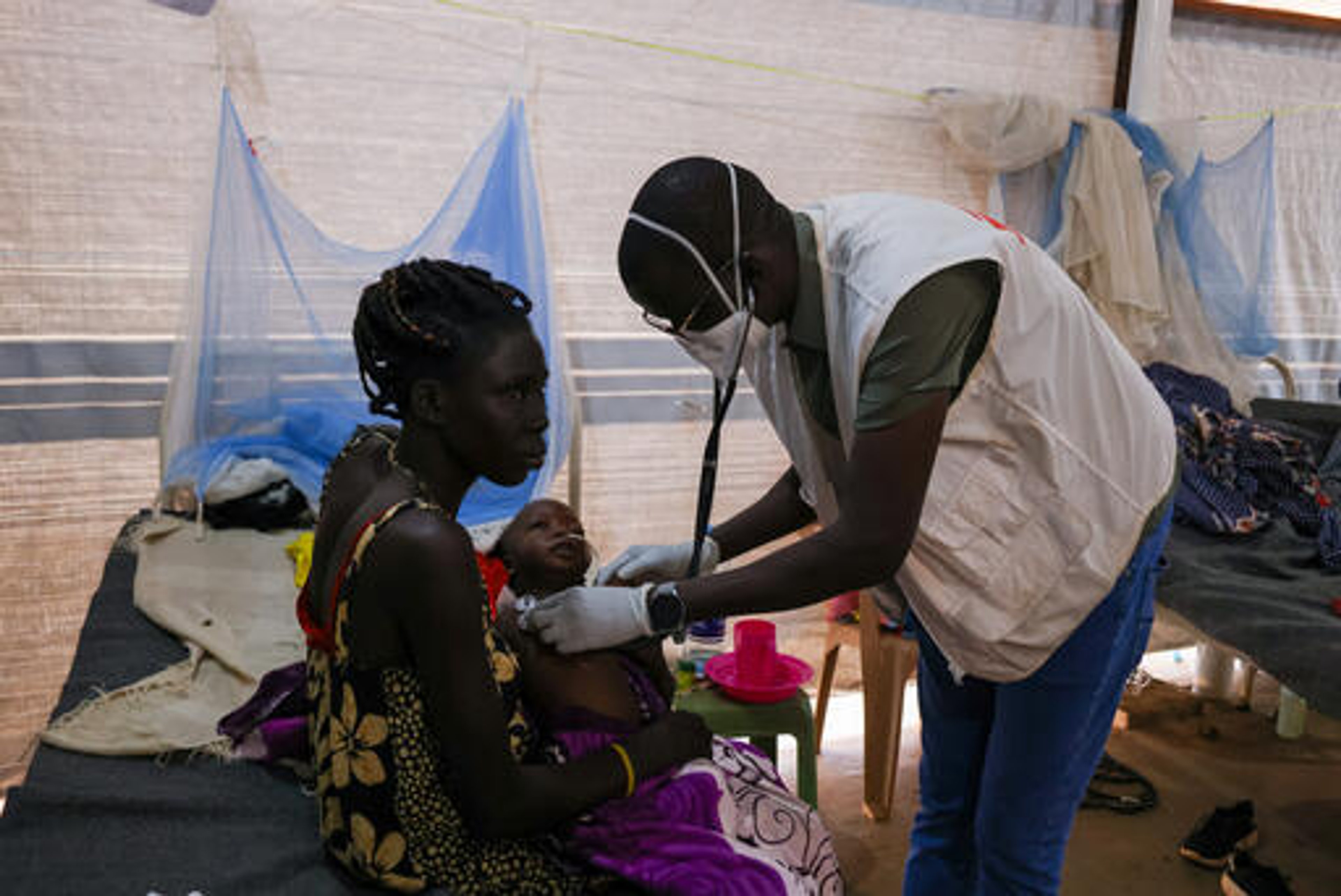 Aluel Garang Kur, 30 years old, holding Dut Garang Athian, one year old, TB positive while being checked by Dr David Aleho, Medical Activity Manager in the TB ward of MSF supported Aweil State Hospital. Aluel Garang Kur is a single mother of four, she is TB positive as well and stopped taking medication due to lack of access to medical care and medication.