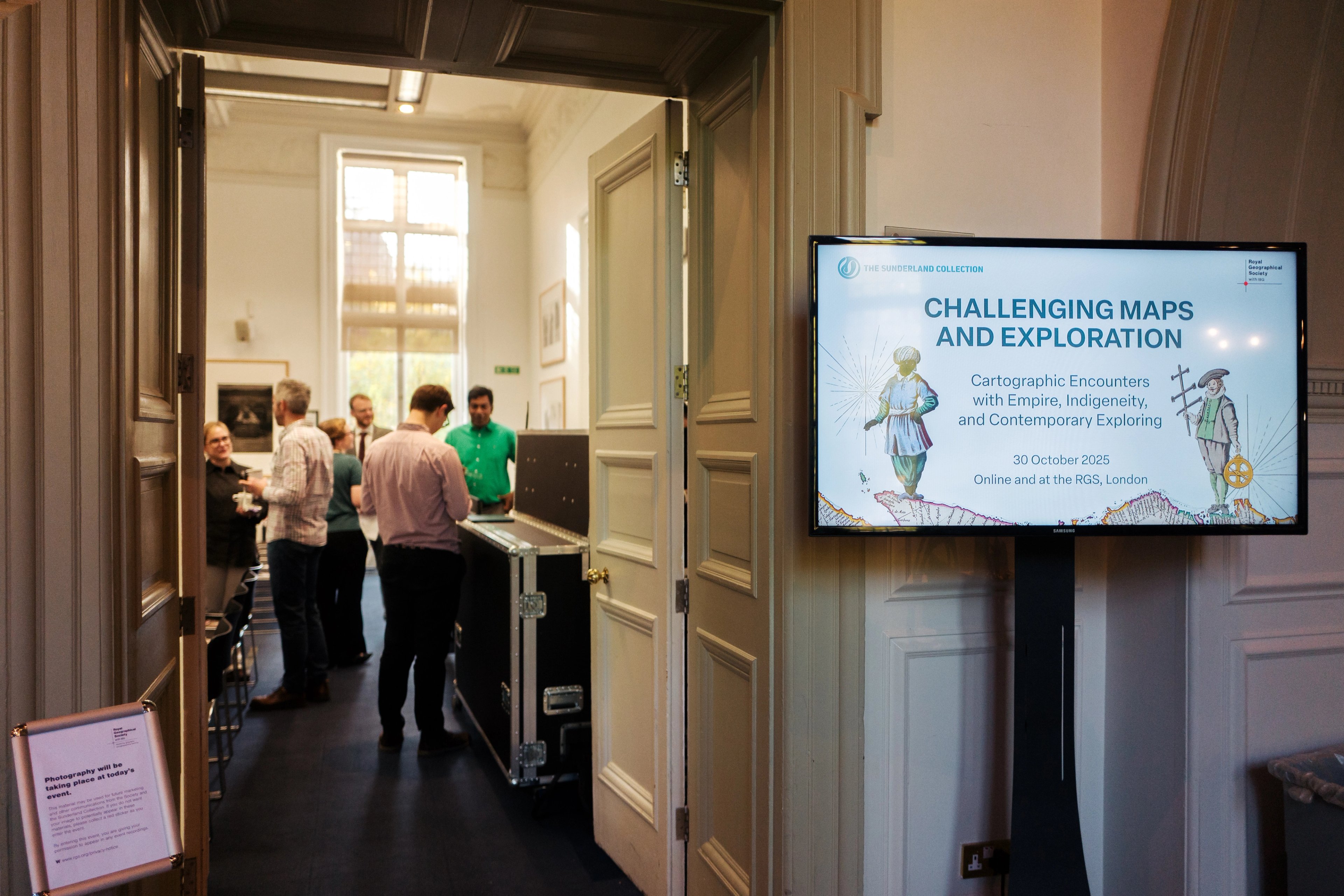 View in the doorway at the Education Centre at the RGS during the Sunderland Symposium 2025. A small gathering of people chat merrily in the sun.