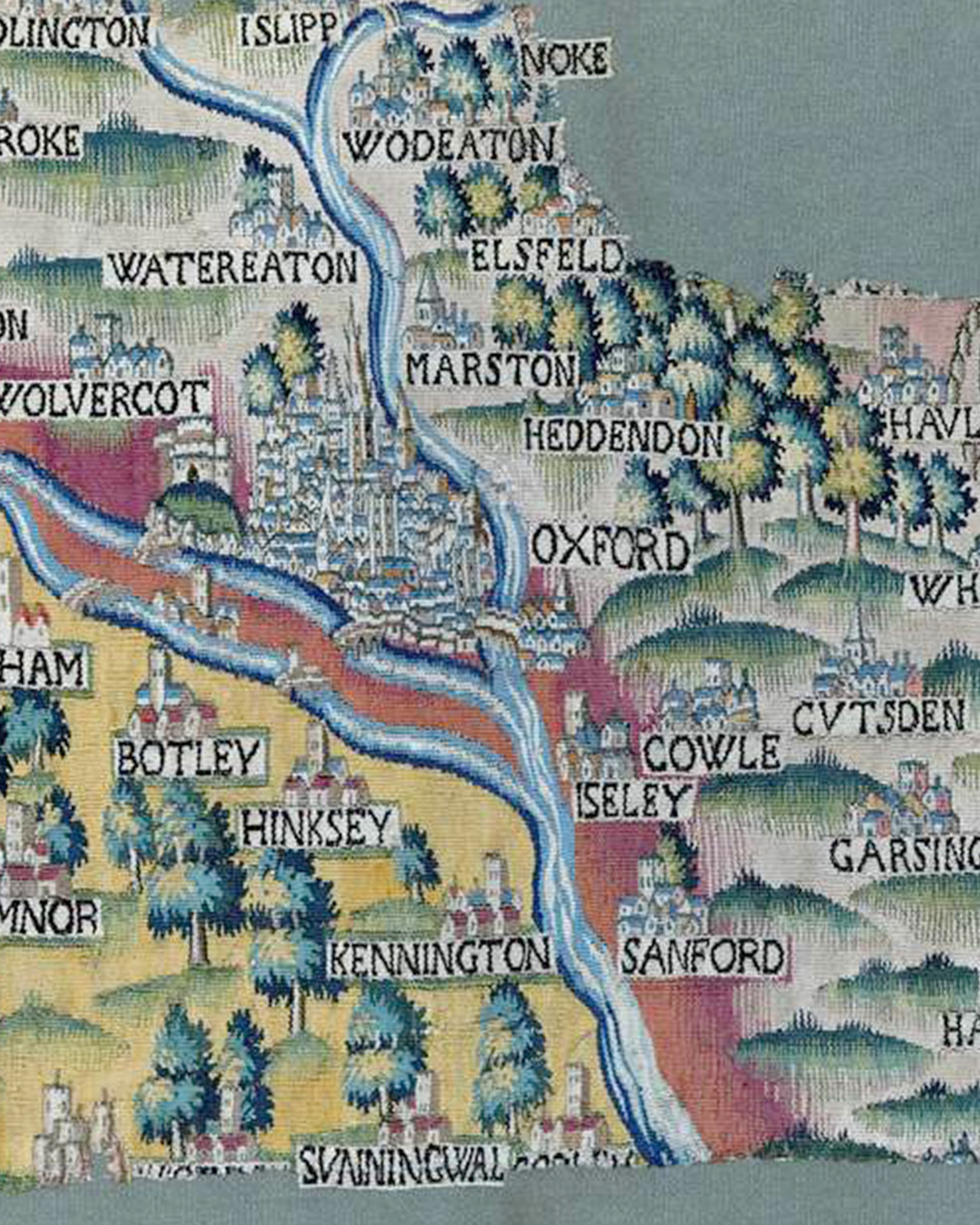 Detail of the Sheldon Tapestry Map of Oxford. The textile map is brightly coloured. It shows the city of Oxford at the centre, which is at the confluence of the River Cherwell and the River Thames. Place names surround the city, as to physical features such as trees and hills. The map is undergoing conservation and has a section of loss in the upper right and lower edge.