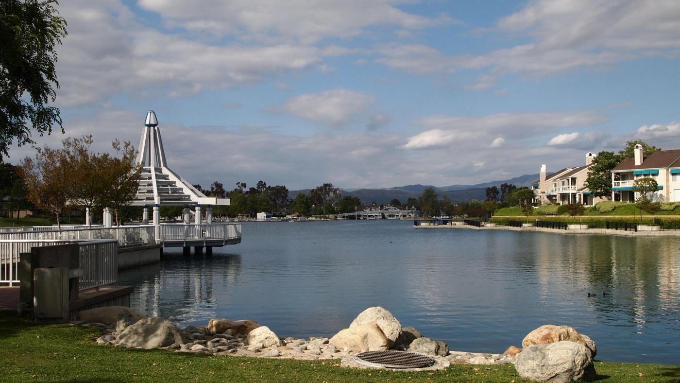 North Lake in Woodbridge, Irvine: a gazebo pier, calm water and lakefront townhomes on a clear day.