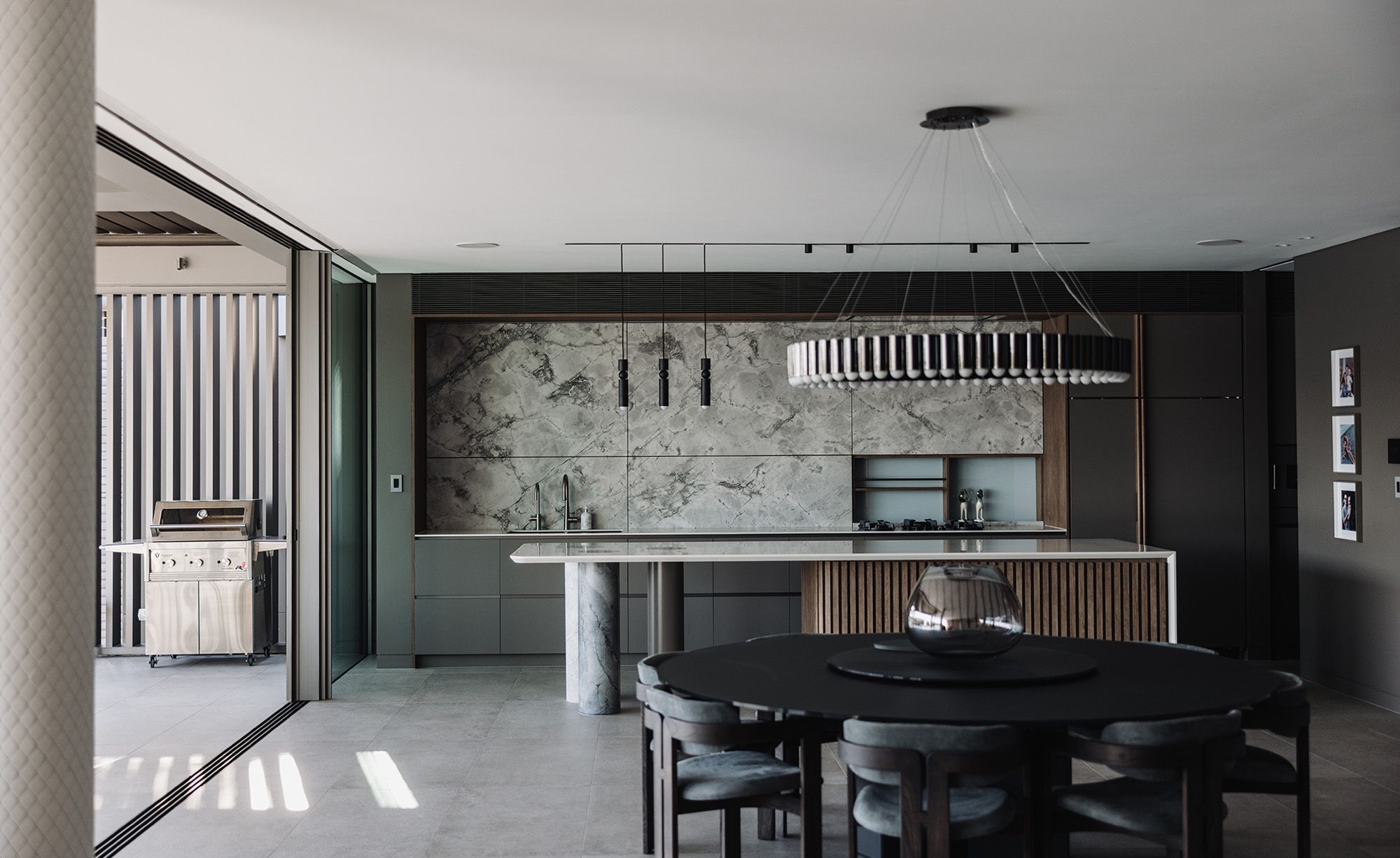 Kitchen and dining room opening to the terrace, with a marble splashback and a long pendant