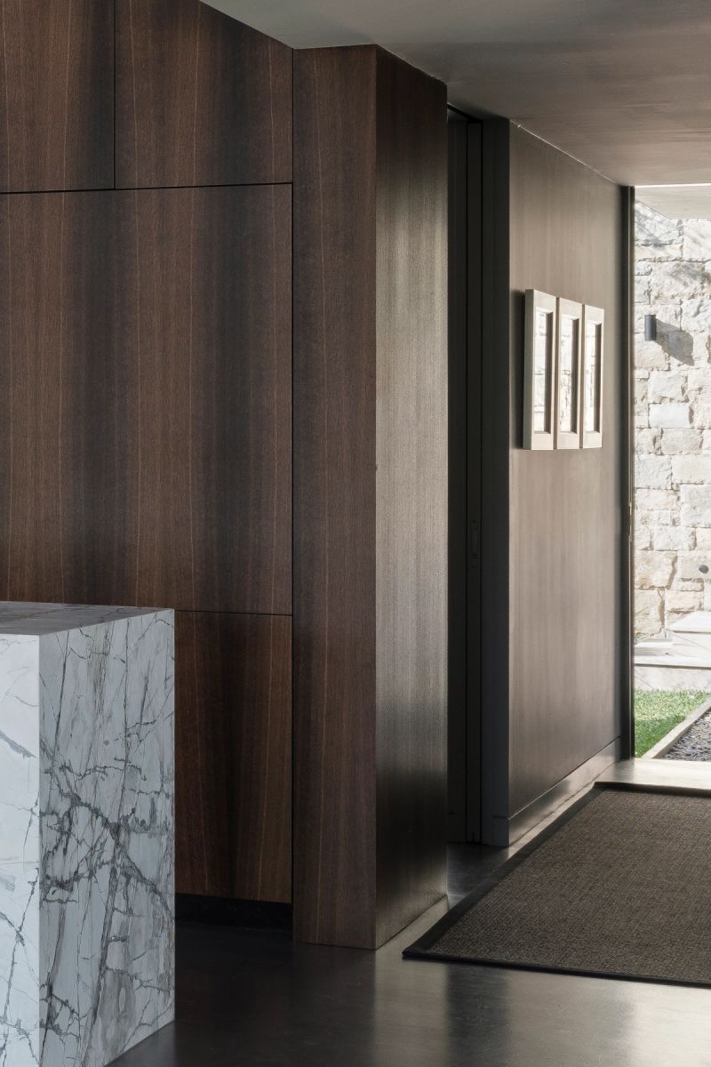 Entry at Shellbank House with dark timber joinery, a marble island and a sandstone wall beyond