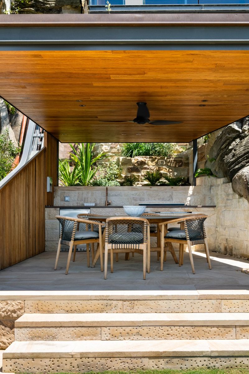 Covered outdoor dining terrace with a timber ceiling and sandstone steps