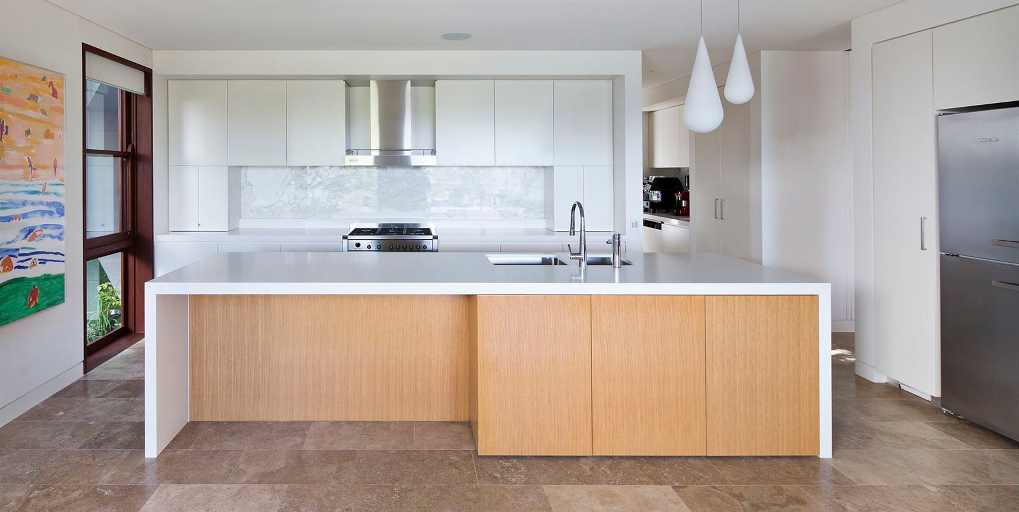 White kitchen with a timber fronted island and a stone floor