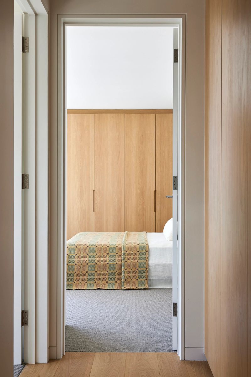 View through timber doorways into a bedroom with a patterned bedspread