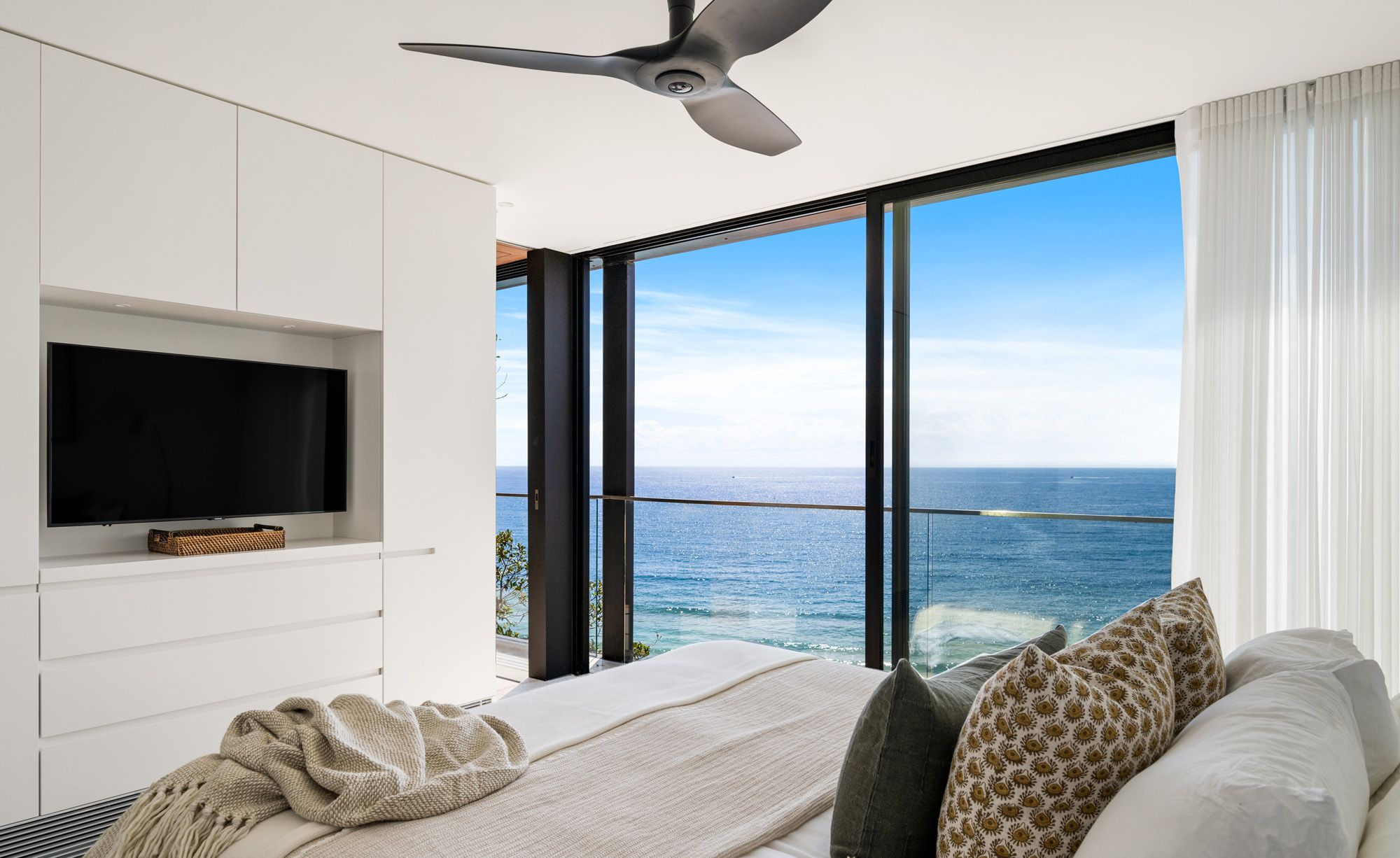 Bedroom with built in joinery and a glass wall to the ocean