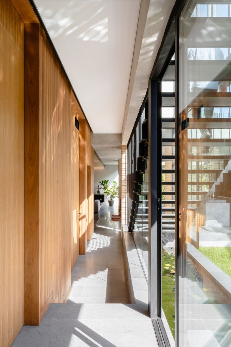 Timber lined hallway beside a glass wall and a slatted stair