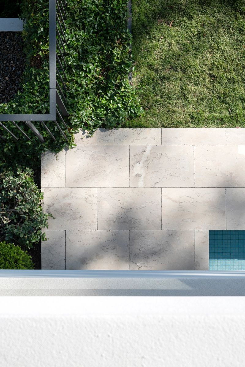 Stone paving and a green wall beside the pool edge at Shellbank House