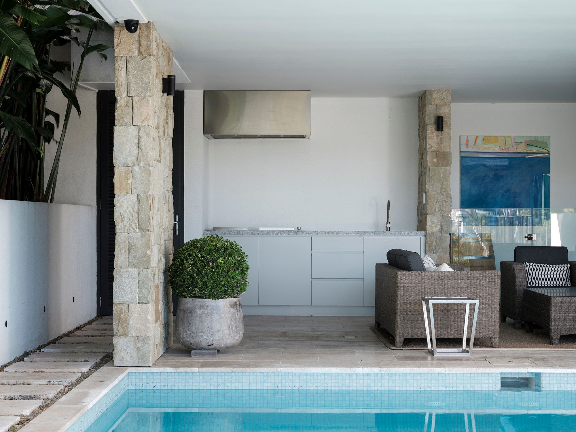 Covered outdoor kitchen beside the pool at Shellbank House, with sandstone columns