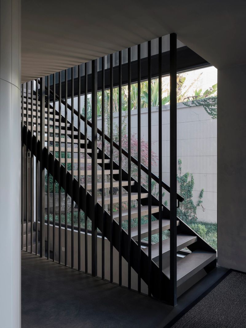 Open steel stair with black balusters, the garden beyond