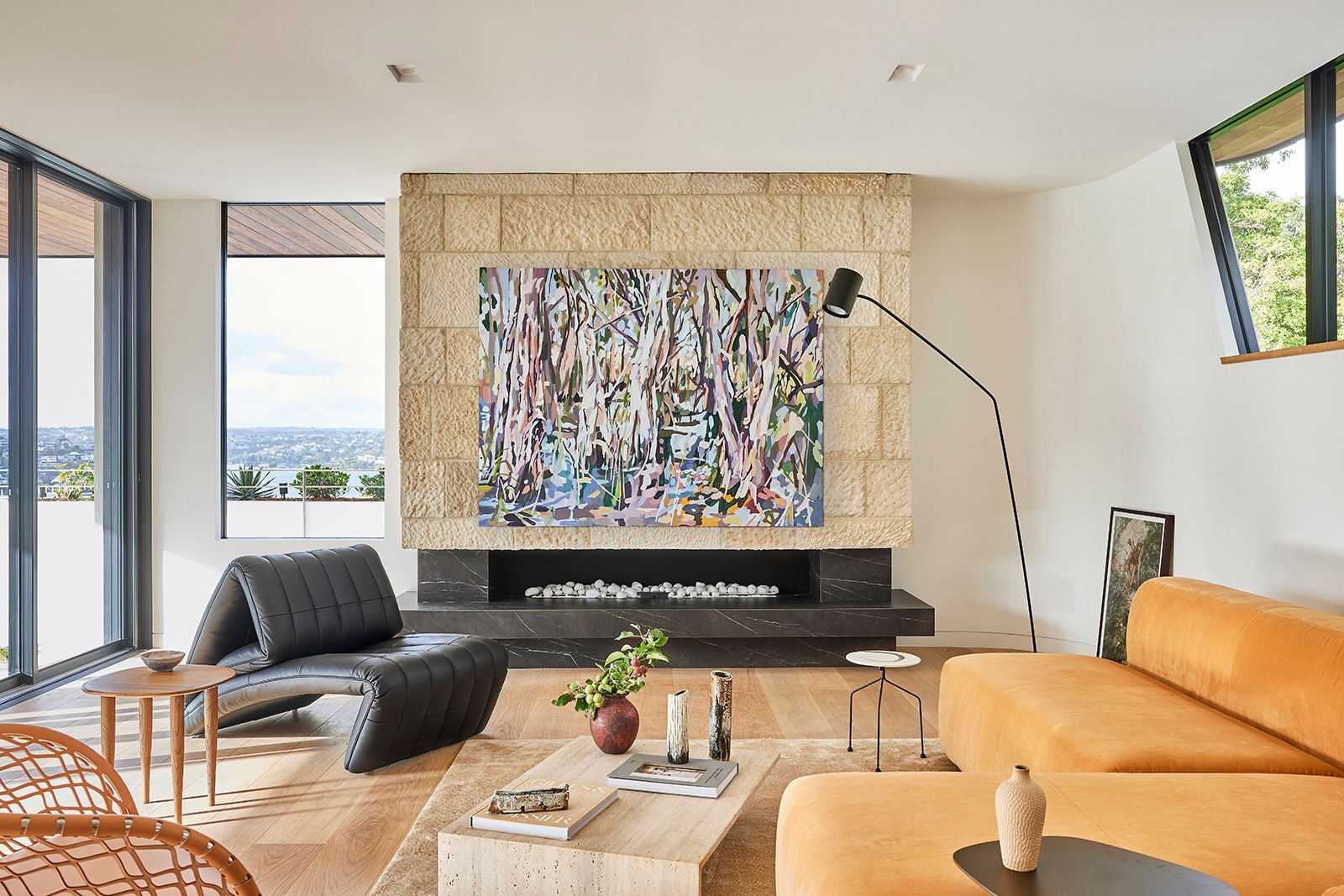 Living room with a sandstone fireplace wall, a large artwork and a tan sofa