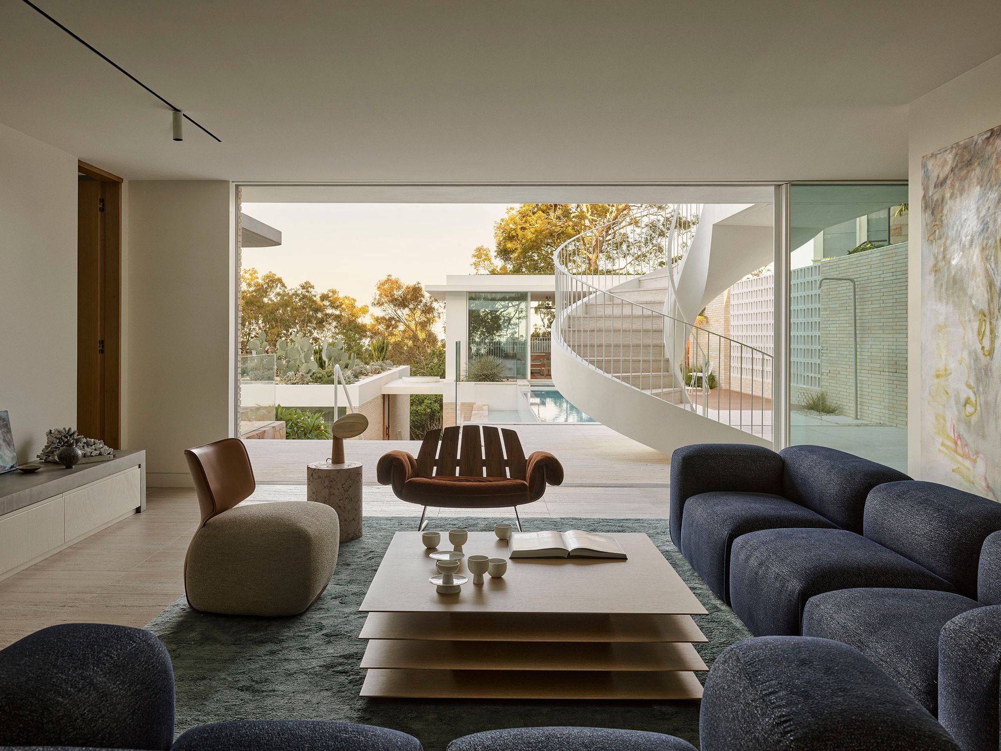 Breeze House living room opening to the terrace, with the spiral stair and pool beyond