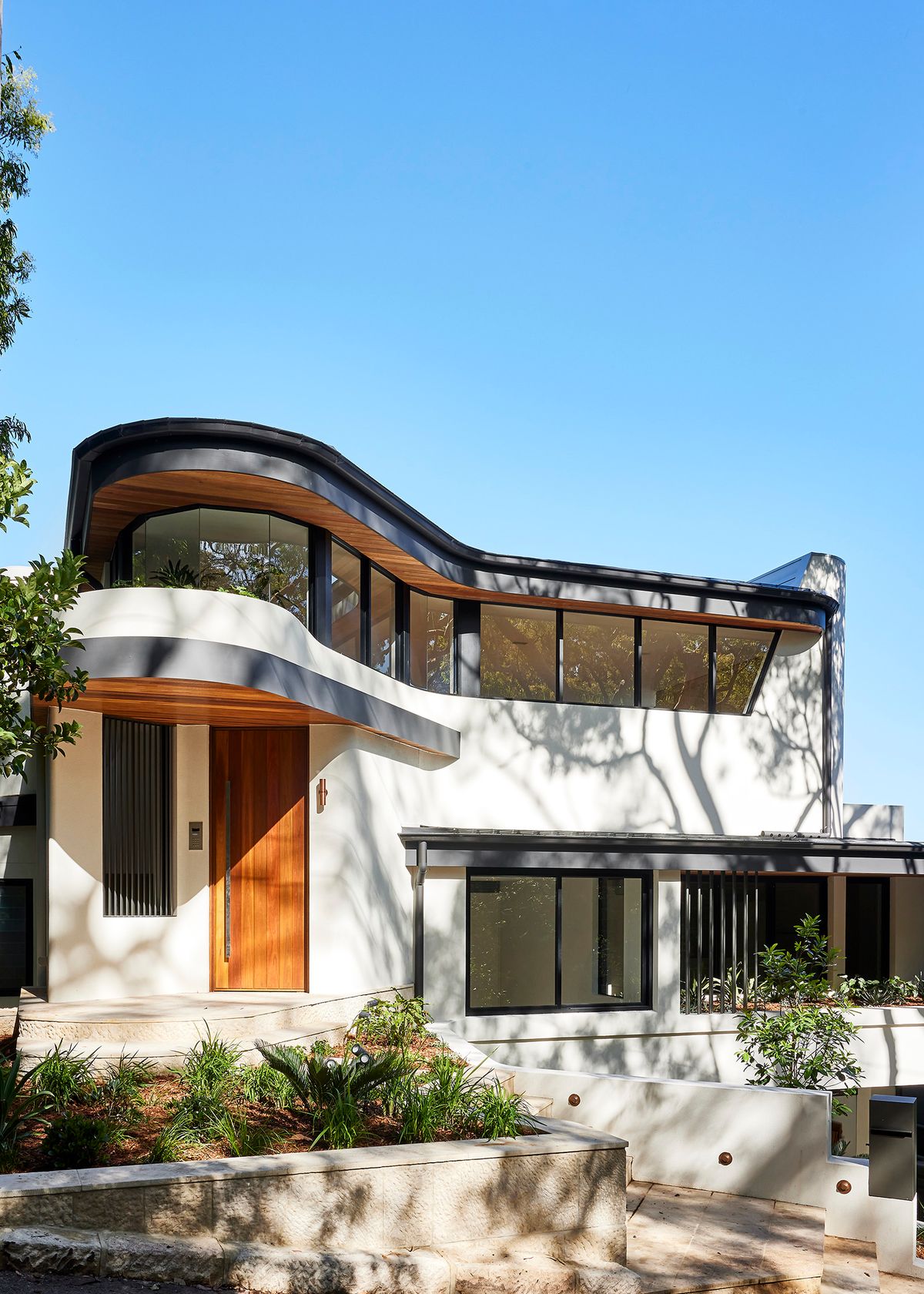 Cobbittee House street facade with curved timber clad balconies and a timber front door