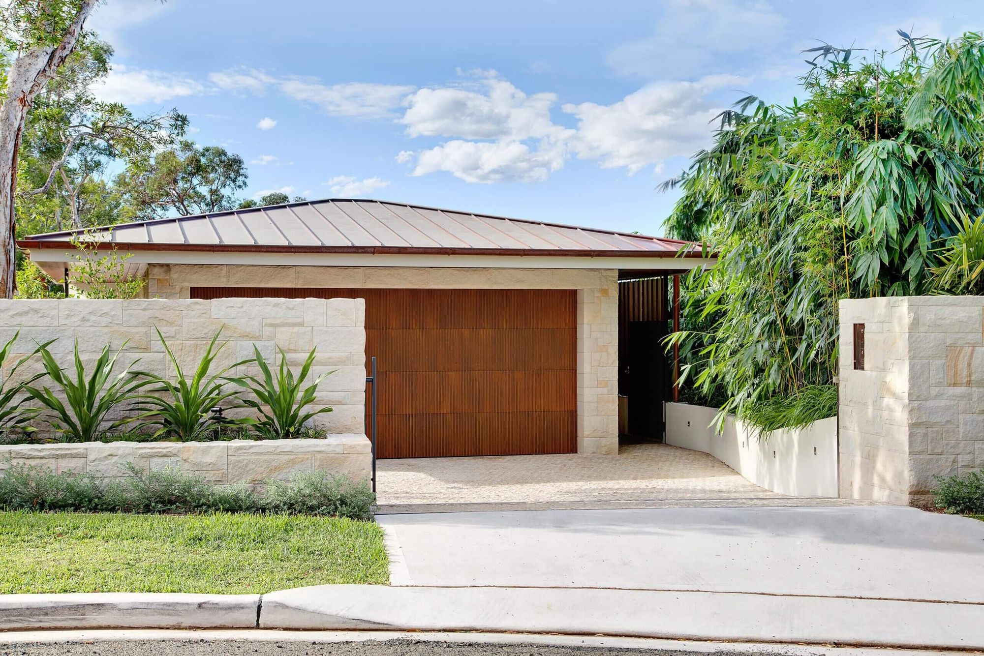Quiet House garage with a timber door, sandstone walls and bamboo