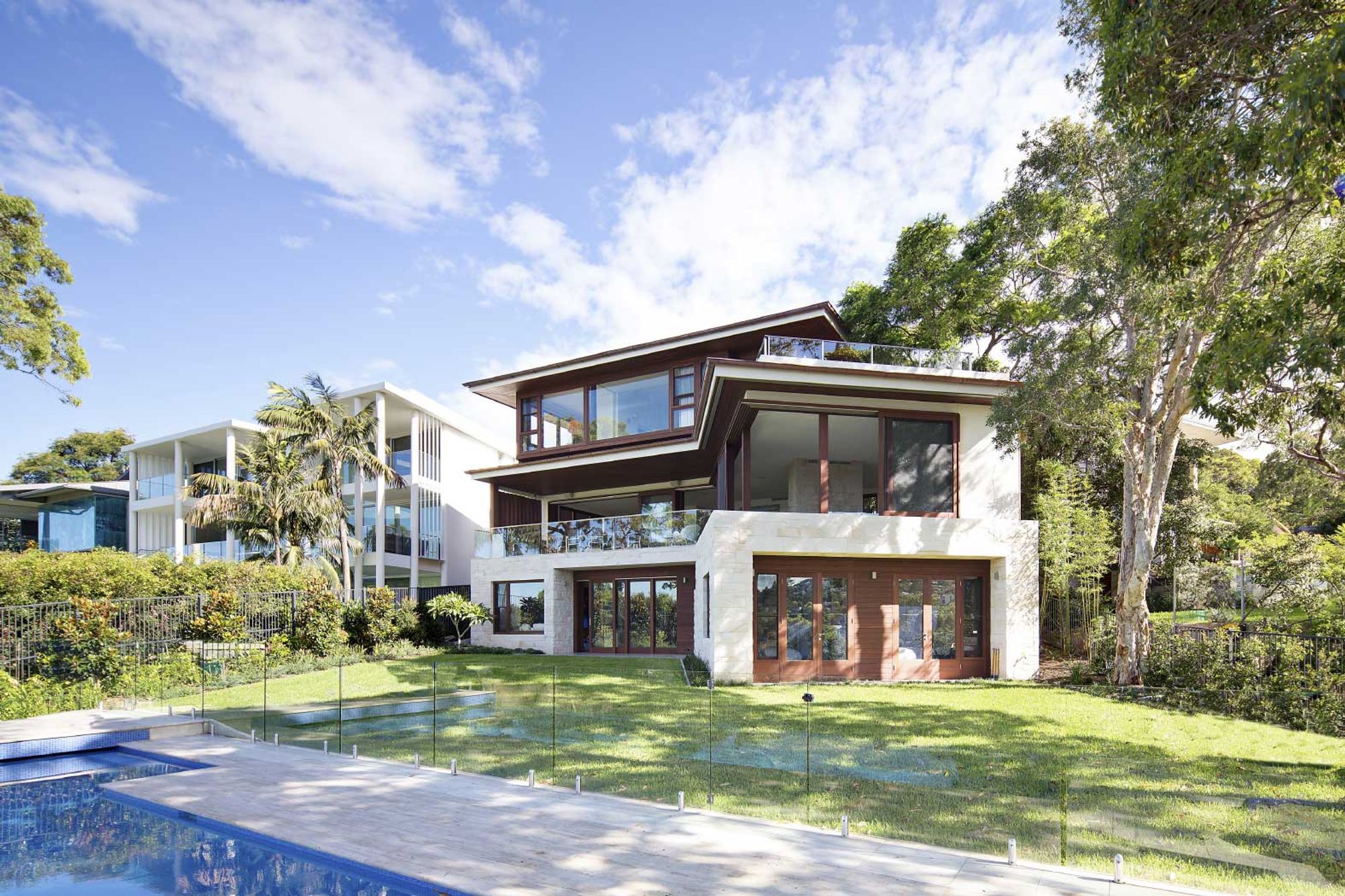 Quiet House from the pool, its sandstone base and timber framed upper storey among the trees