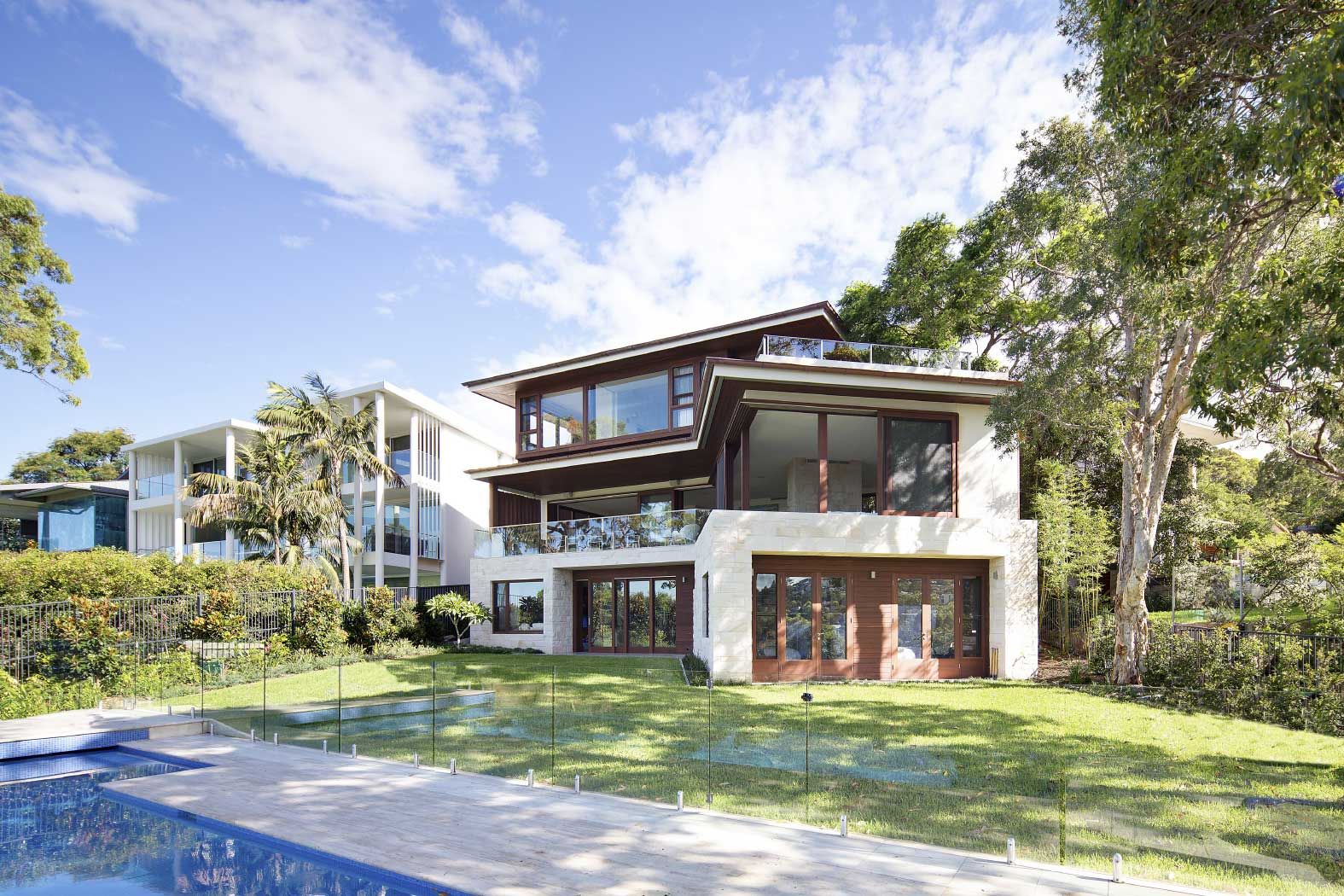 Quiet House from the pool, its sandstone base and timber framed upper storey among the trees
