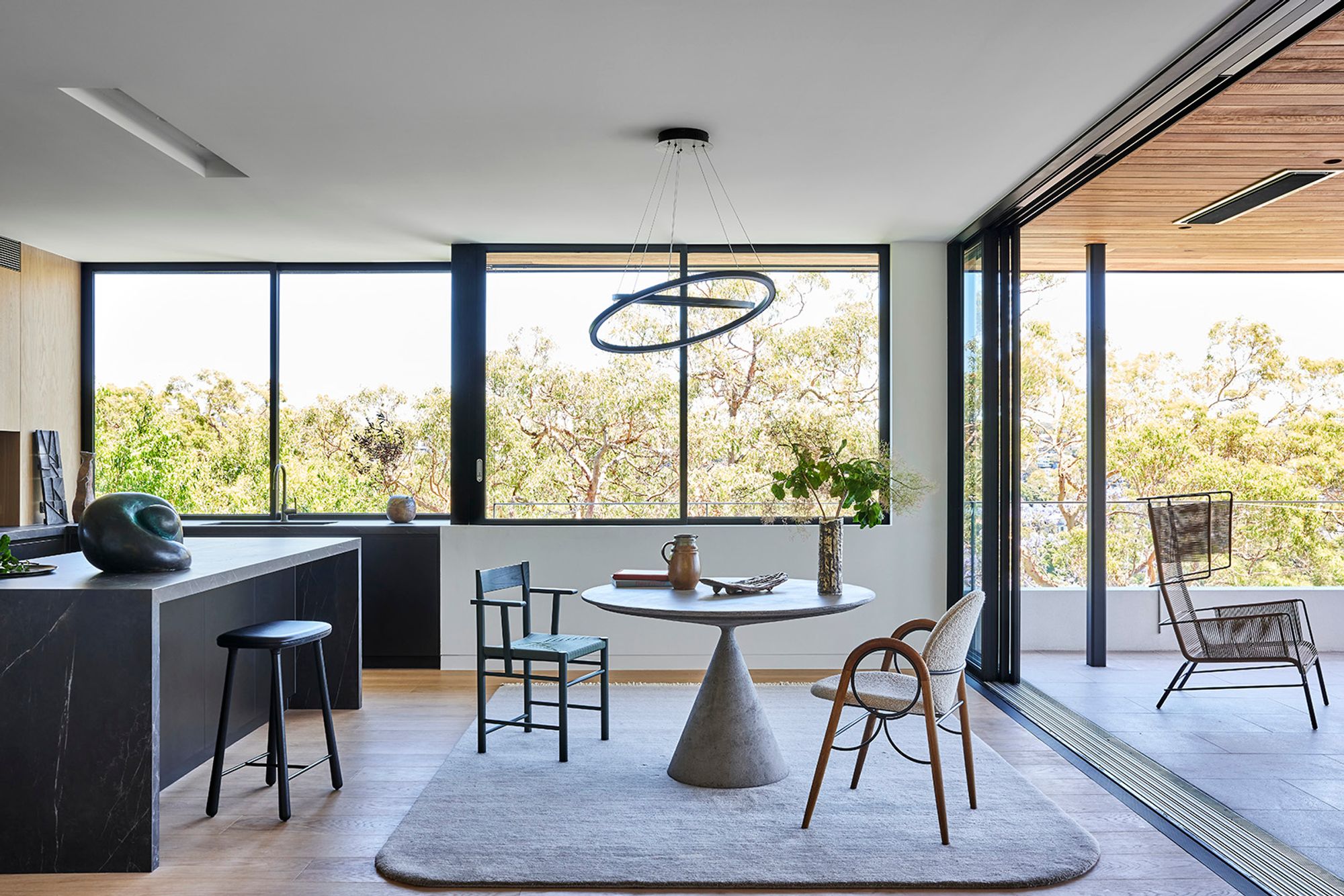 Dining room with a black stone island and a round table, opening to the terrace