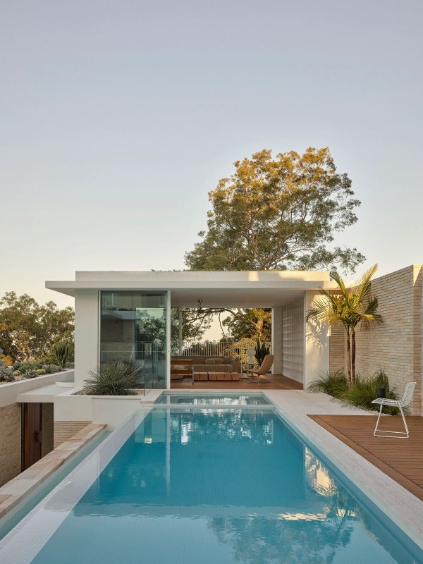 Breeze House pool terrace at dusk, looking to the pavilion and a gum tree beyond