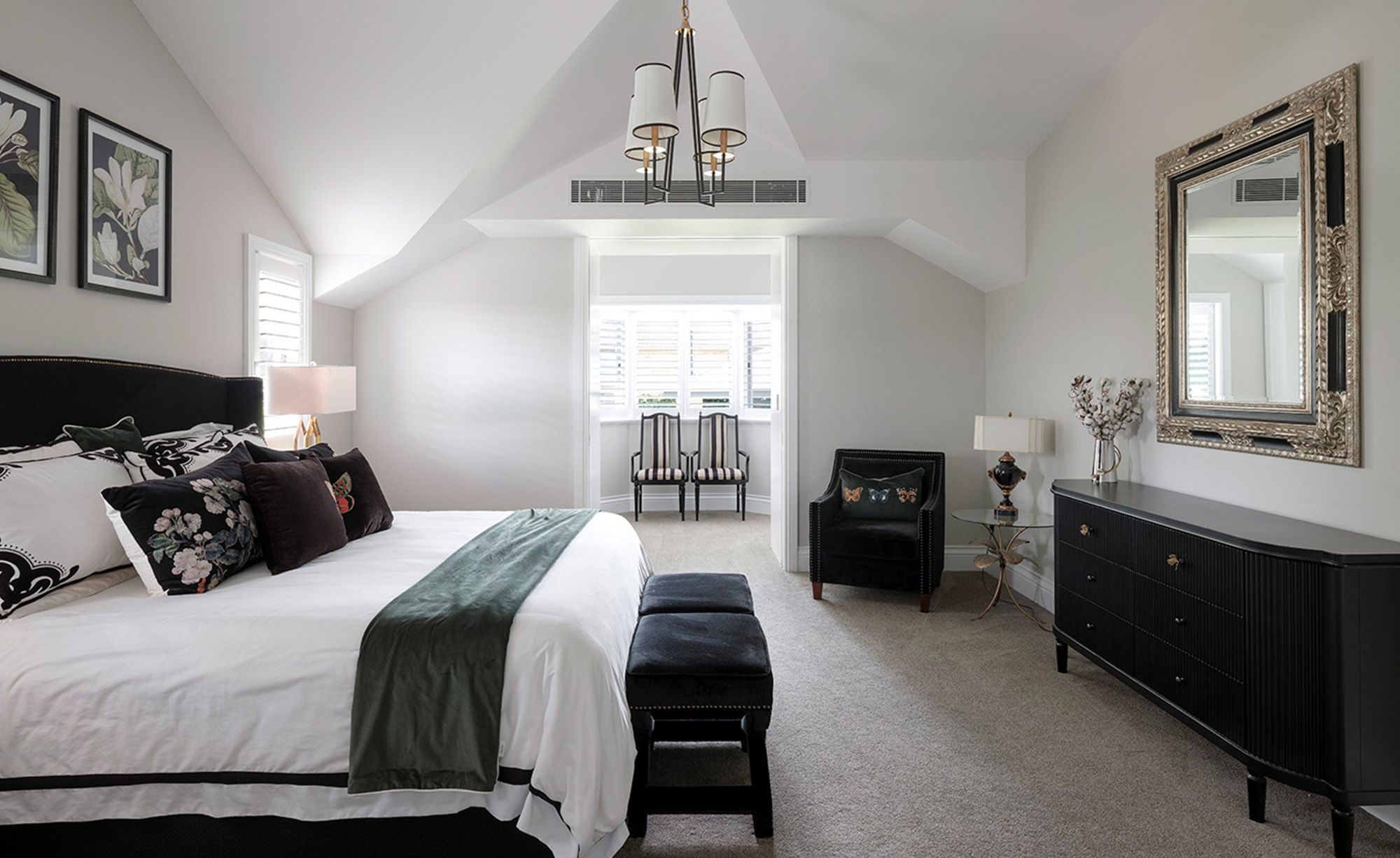 Bedroom with a black bedhead, dark dresser and a gilt mirror