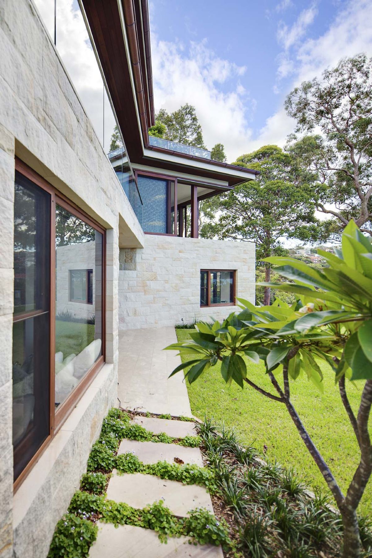 Sandstone facade of Quiet House with stepping stones across the lawn