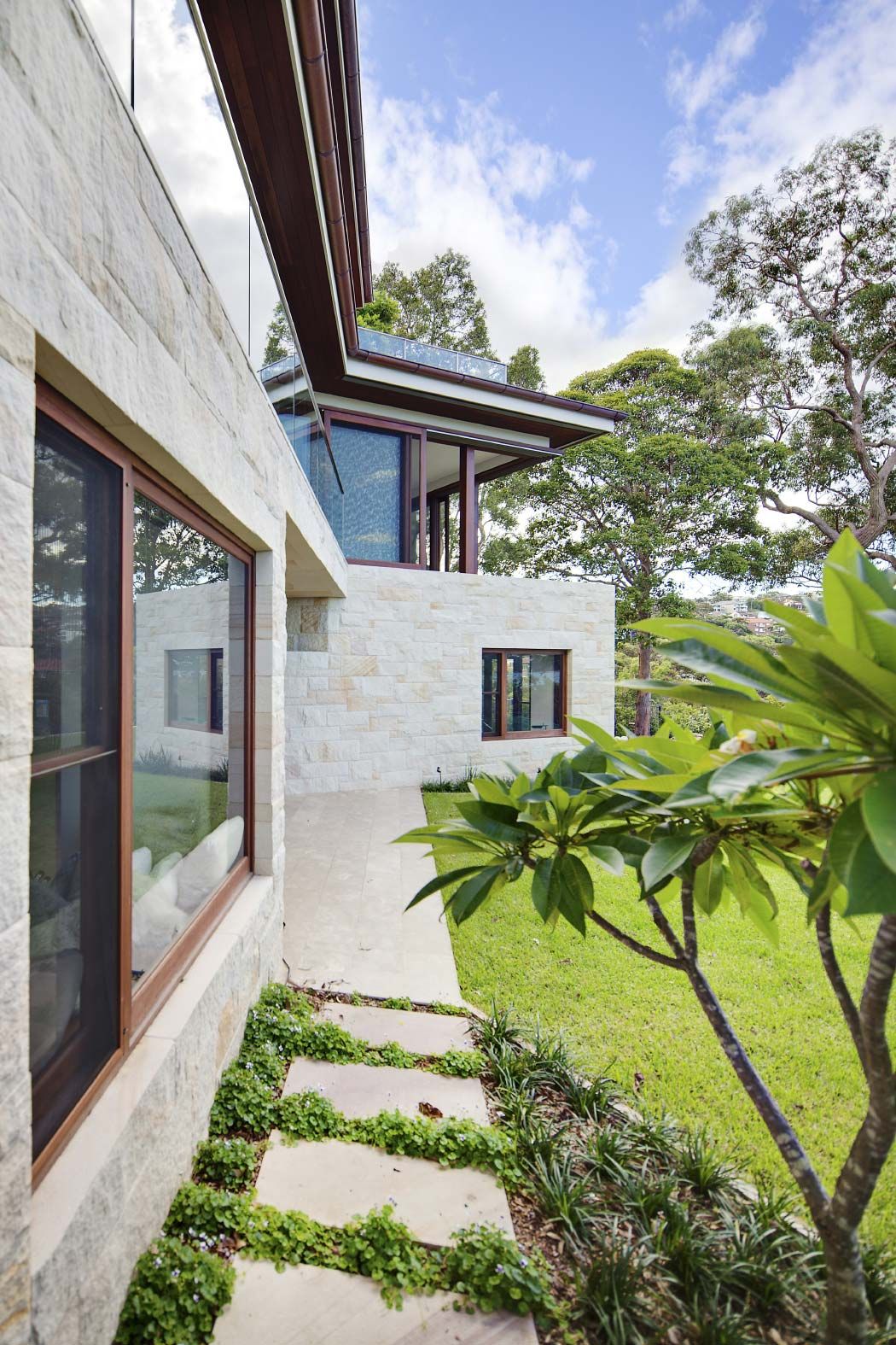 Sandstone facade of Quiet House with stepping stones across the lawn