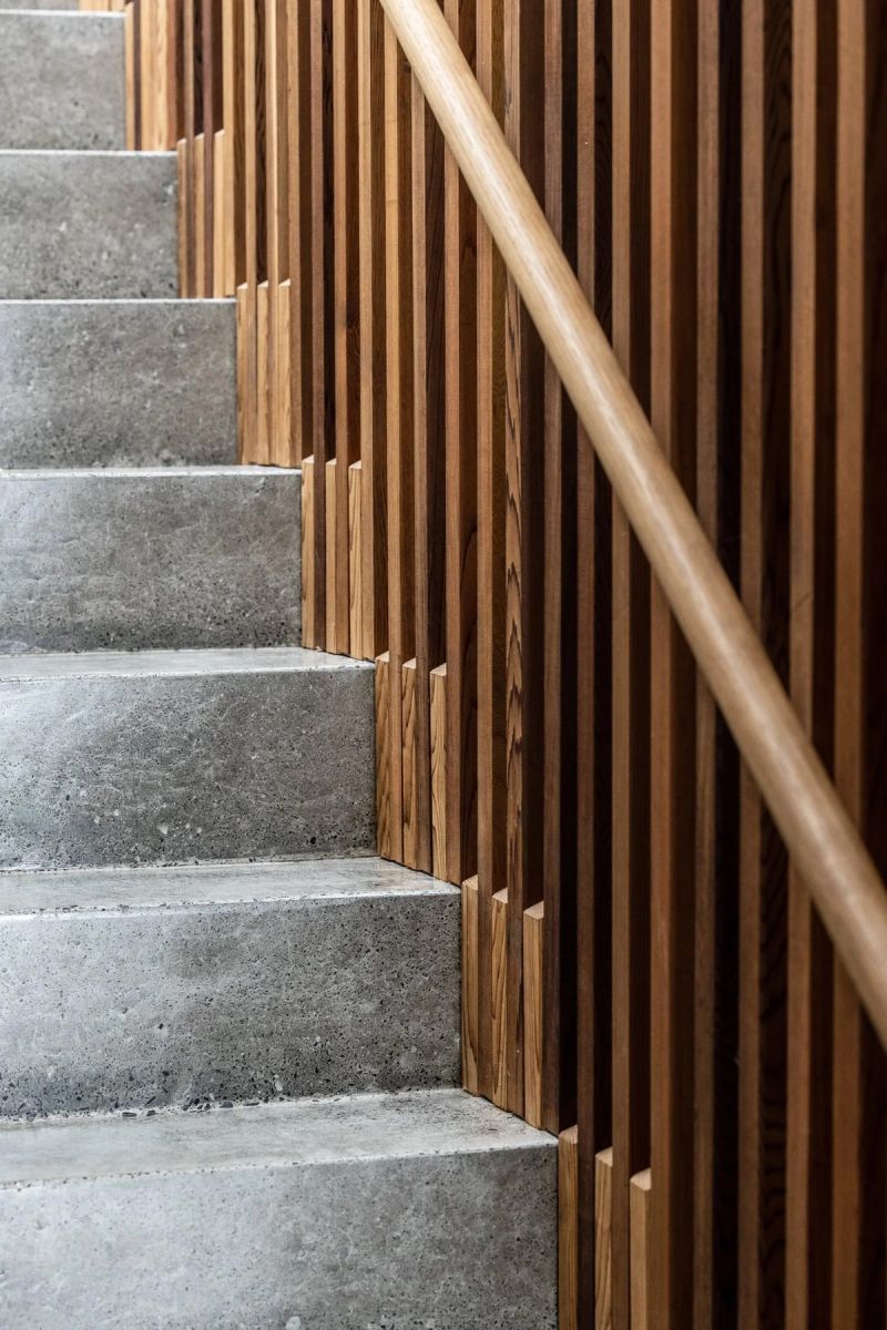 Concrete stair beside a timber batten screen with a curved handrail