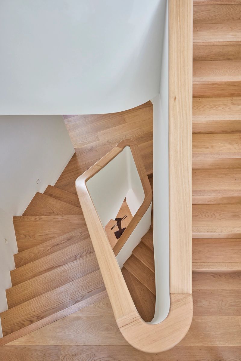 Curved timber staircase seen from above, its balustrade folding around the landing
