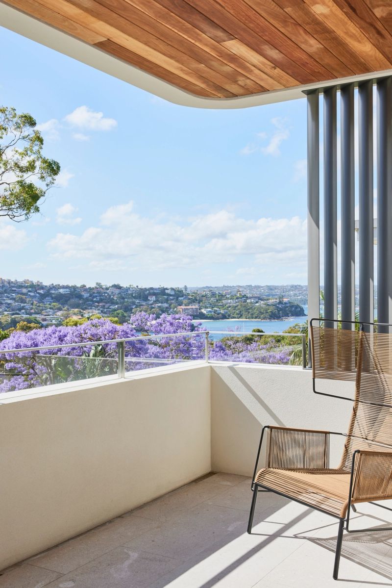 Balcony at Cobbittee House with a wicker chair and a view over the jacarandas to the harbour
