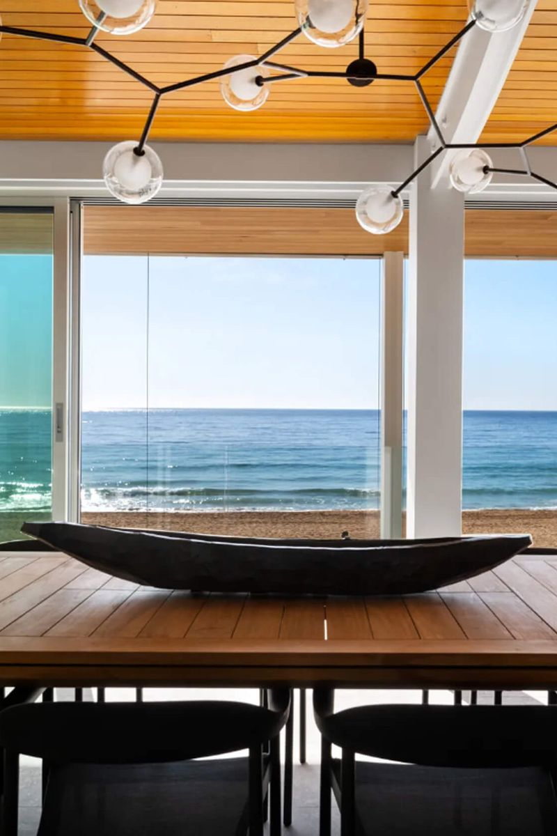 Dining table with a carved timber vessel and ocean views at Swell and High Swell
