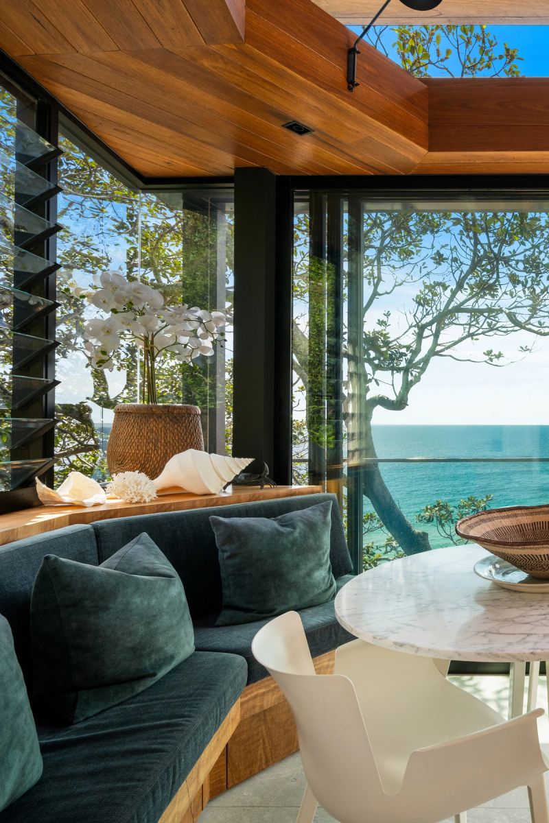 Window seat with dark green cushions and a marble table, the ocean beyond